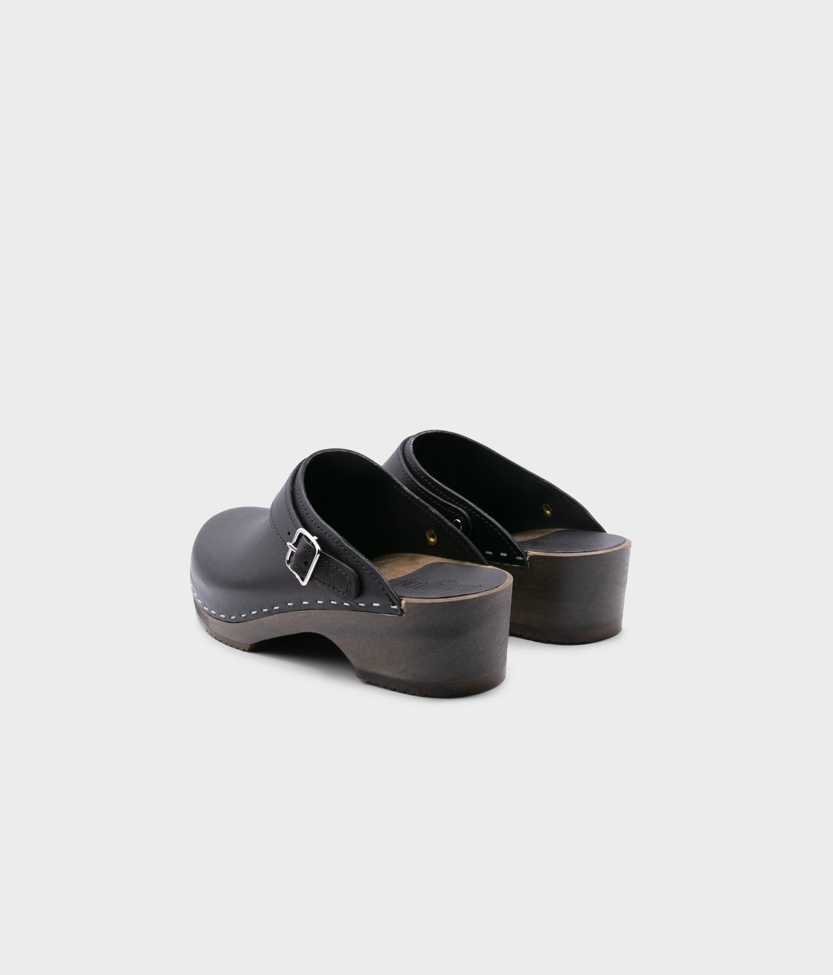 men's low heeled clog mules in black vegetable tanned leather stapled on a dark wooden base with a sling back