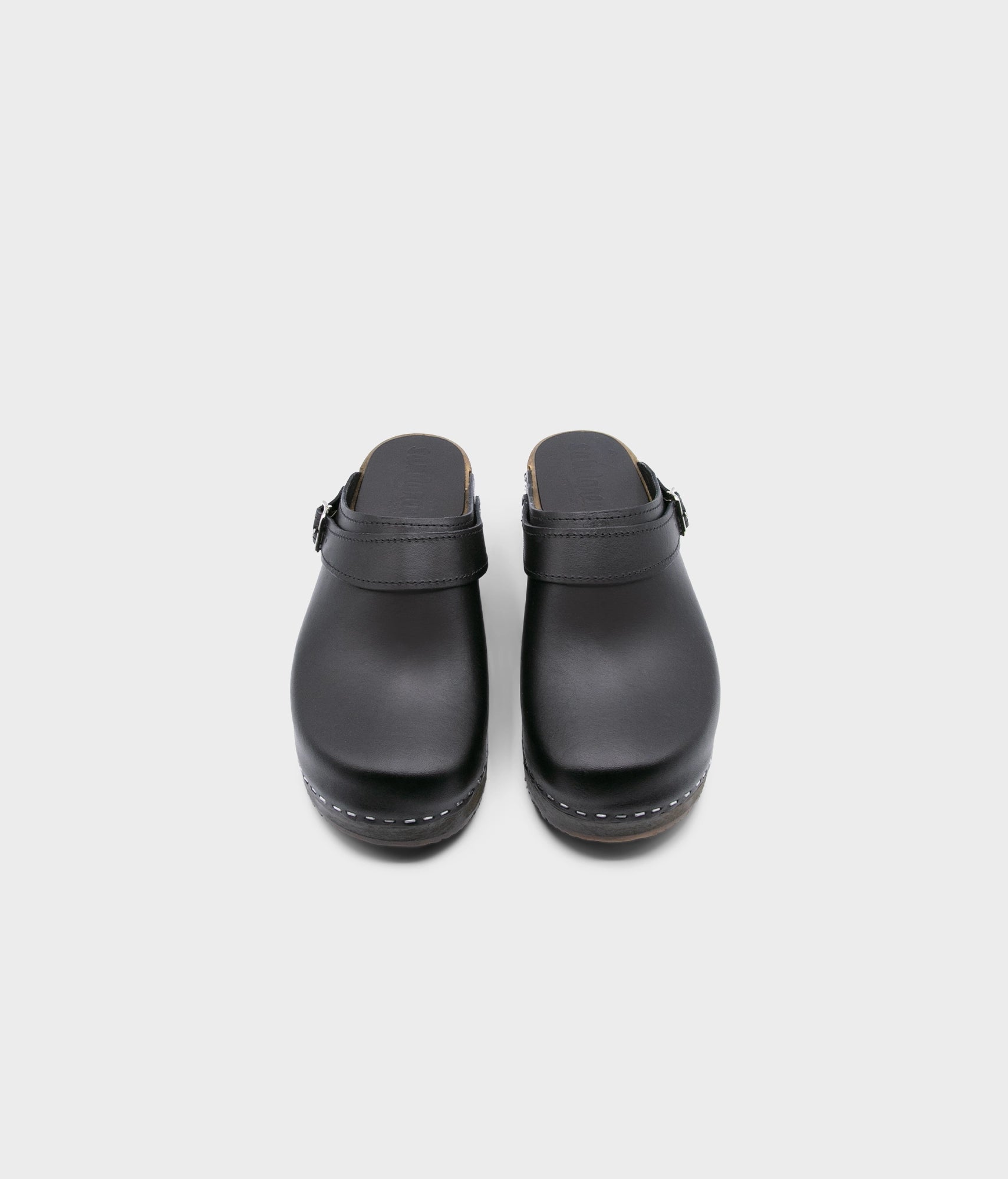 men's low heeled clog mules in black vegetable tanned leather stapled on a dark wooden base with a sling back