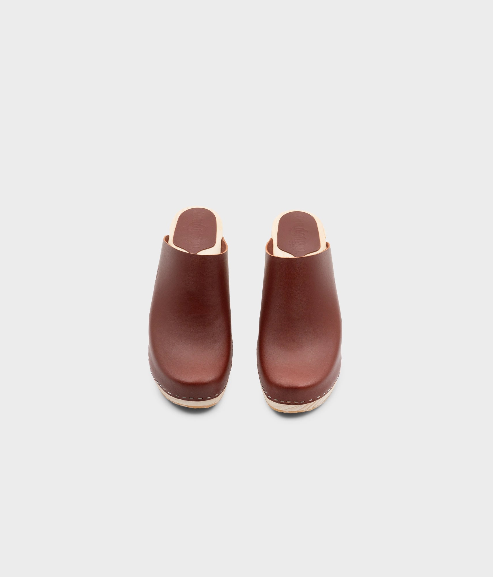 high rise minimalistic clog mule in cognac red vegetable tanned leather stapled on a light wooden base