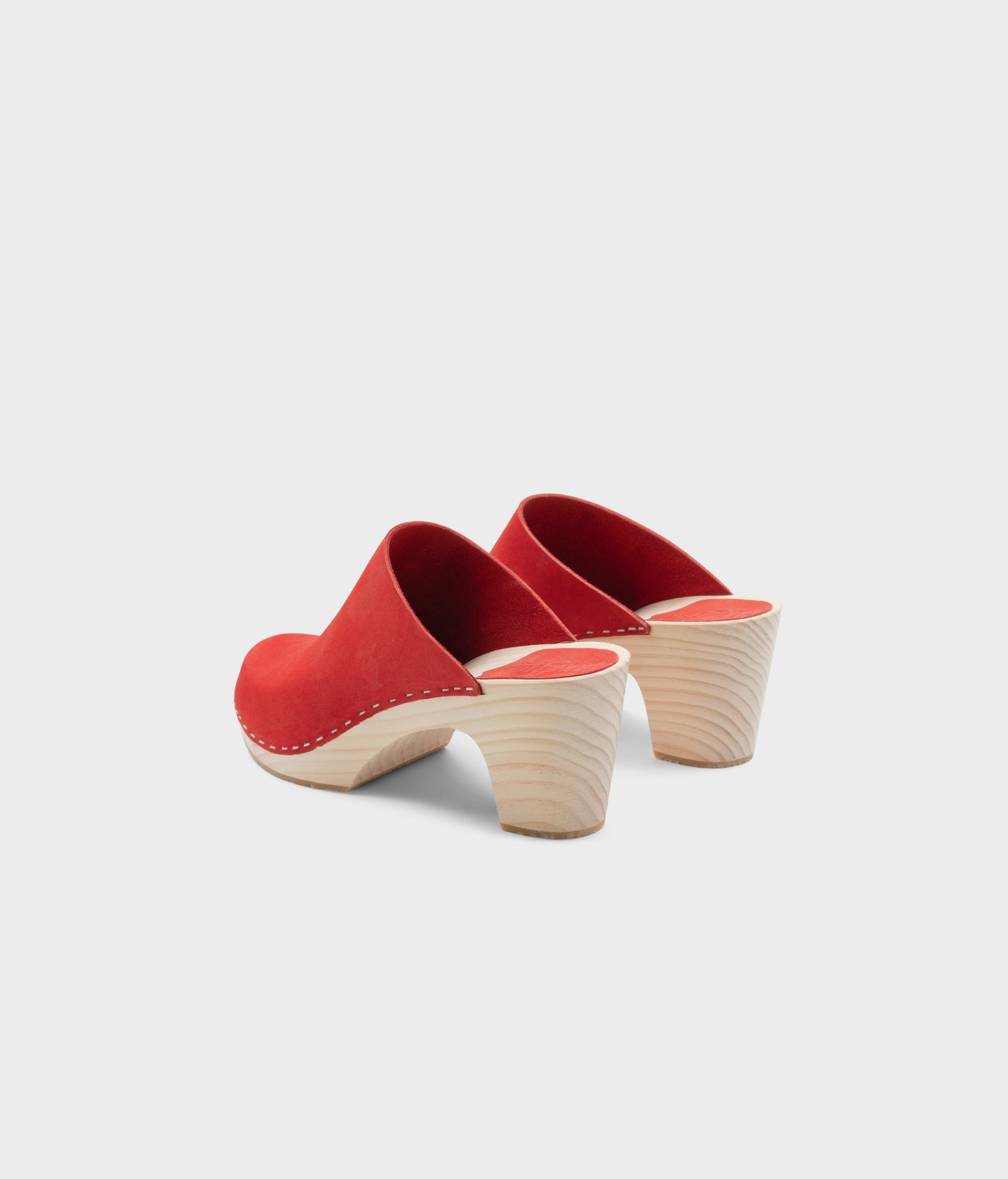 high rise minimalistic clog mule in red nubuck leather stapled on a light wooden base