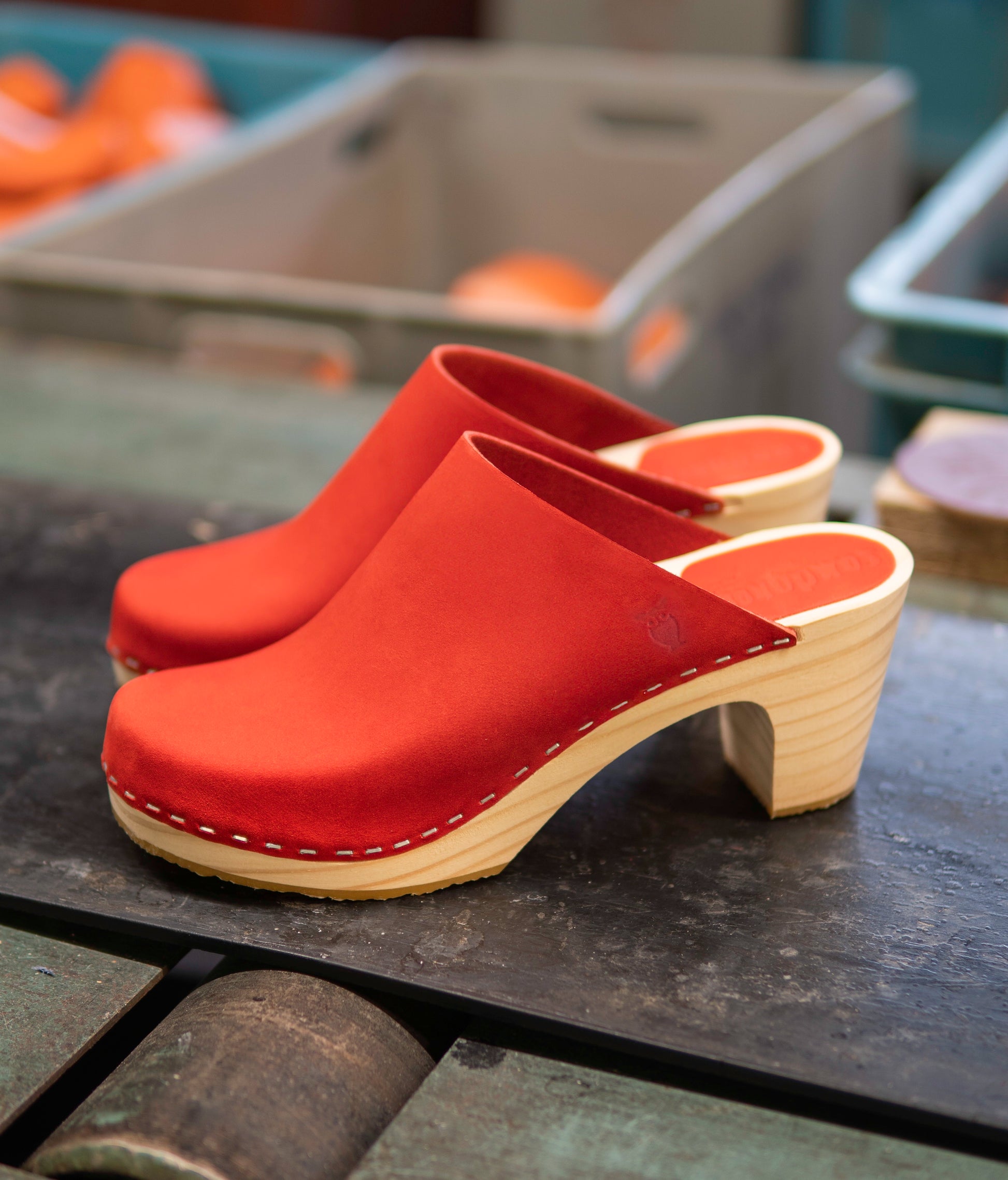 high rise minimalistic clog mule in red nubuck leather stapled on a light wooden base