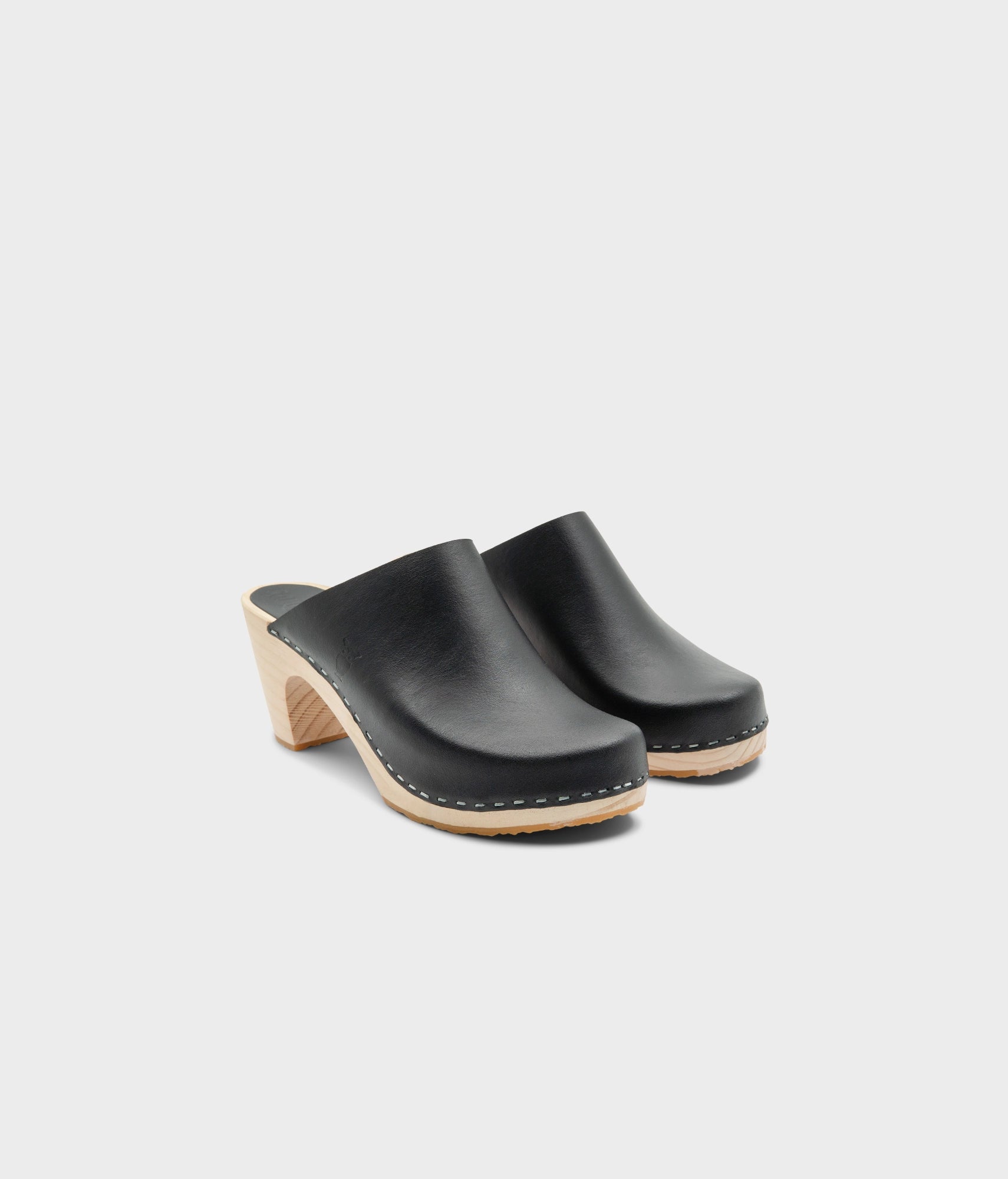 high rise minimalistic clog mule in black vegetable tanned leather stapled on a light wooden base