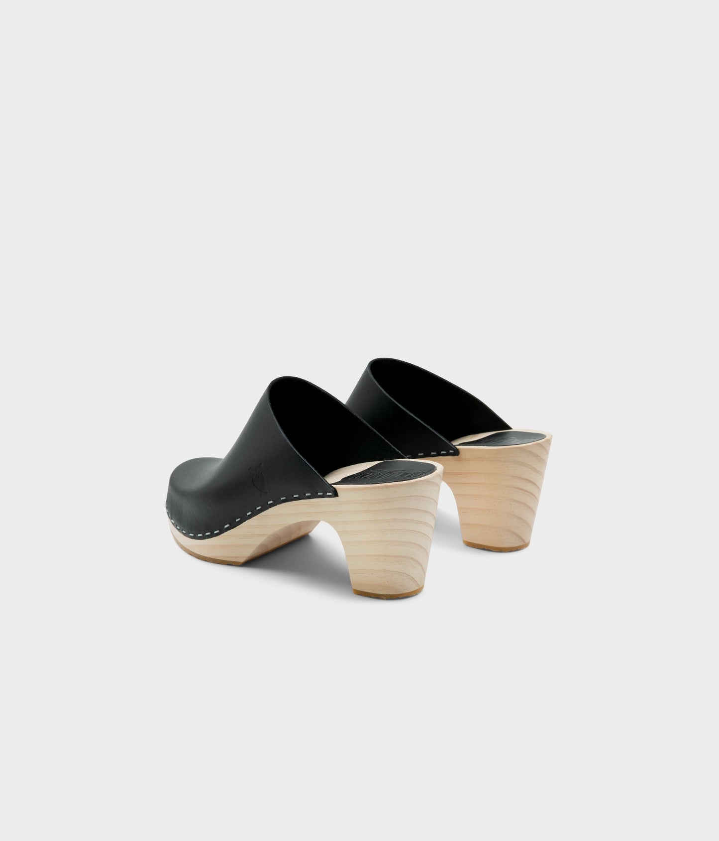 high rise minimalistic clog mule in black vegetable tanned leather stapled on a light wooden base