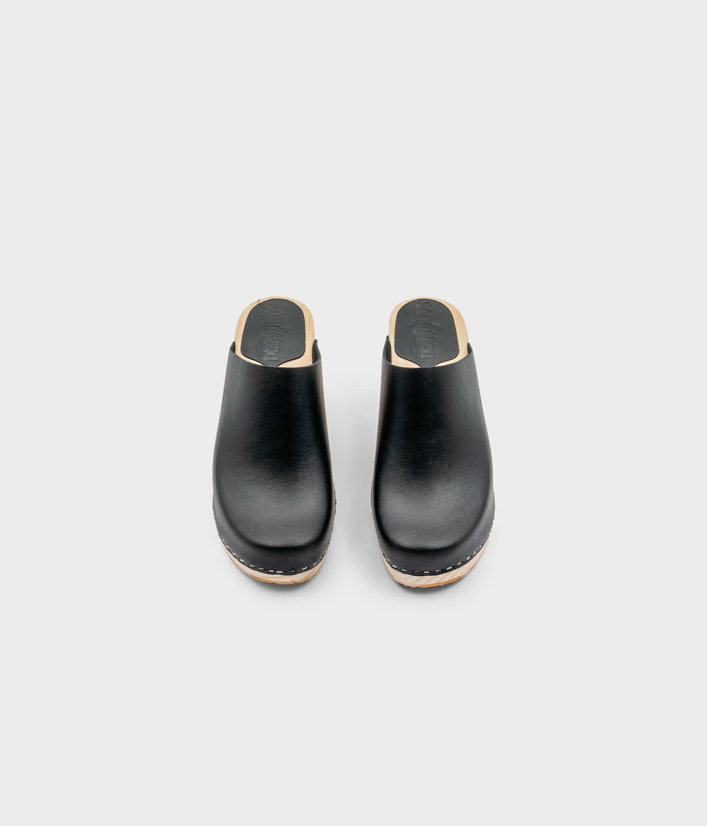 high rise minimalistic clog mule in black vegetable tanned leather stapled on a light wooden base