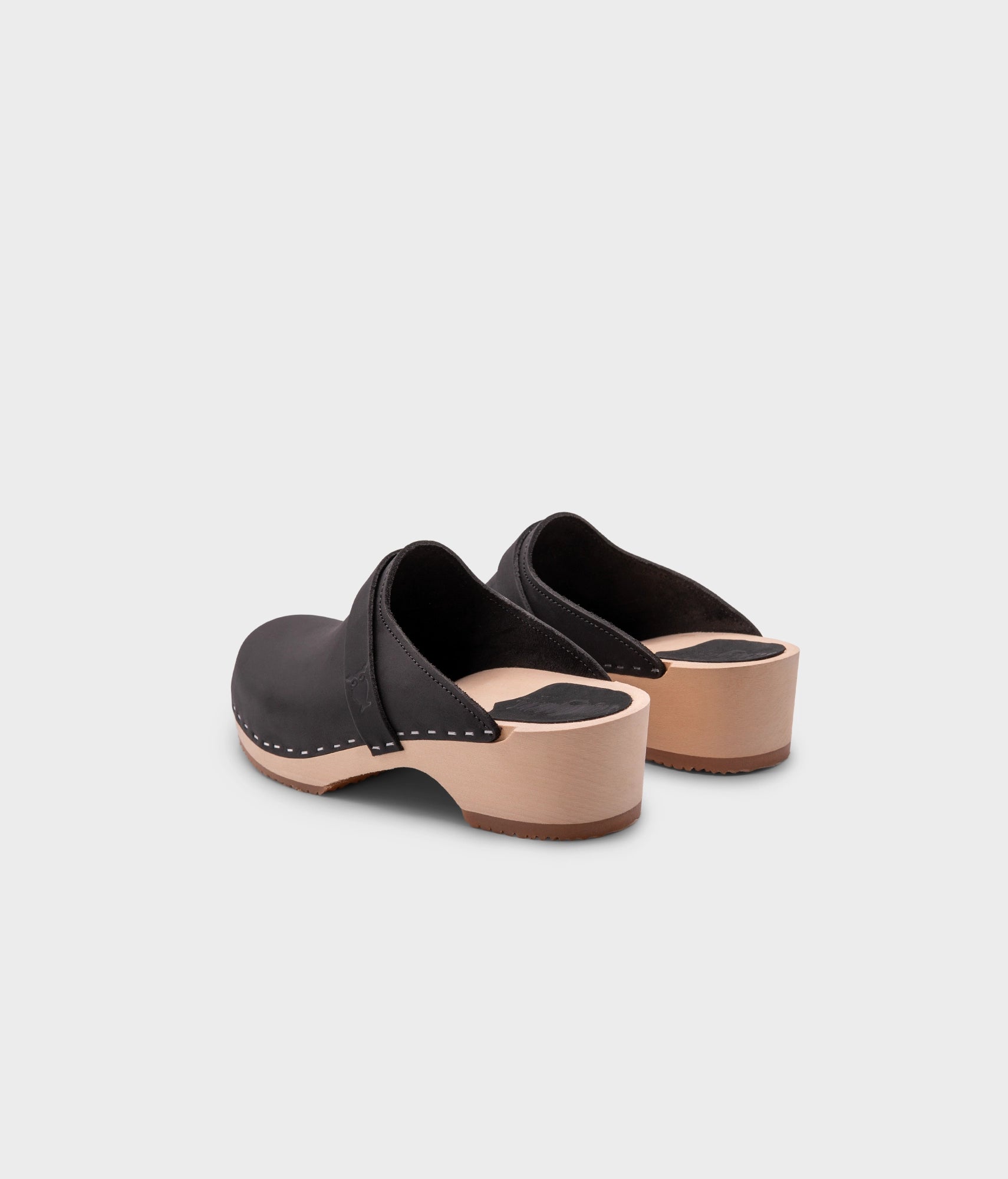 classic low heeled clog mule in black nubuck leather stapled on a light wooden base with a leather strap