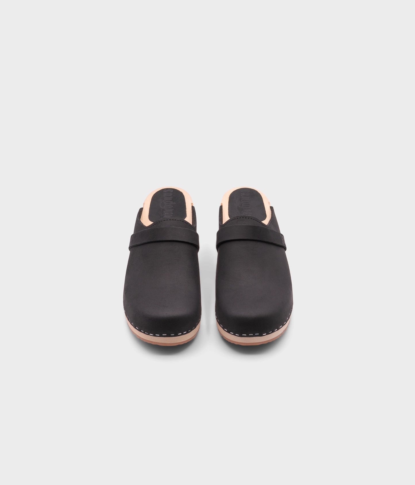 classic low heeled clog mule in black nubuck leather stapled on a light wooden base with a leather strap