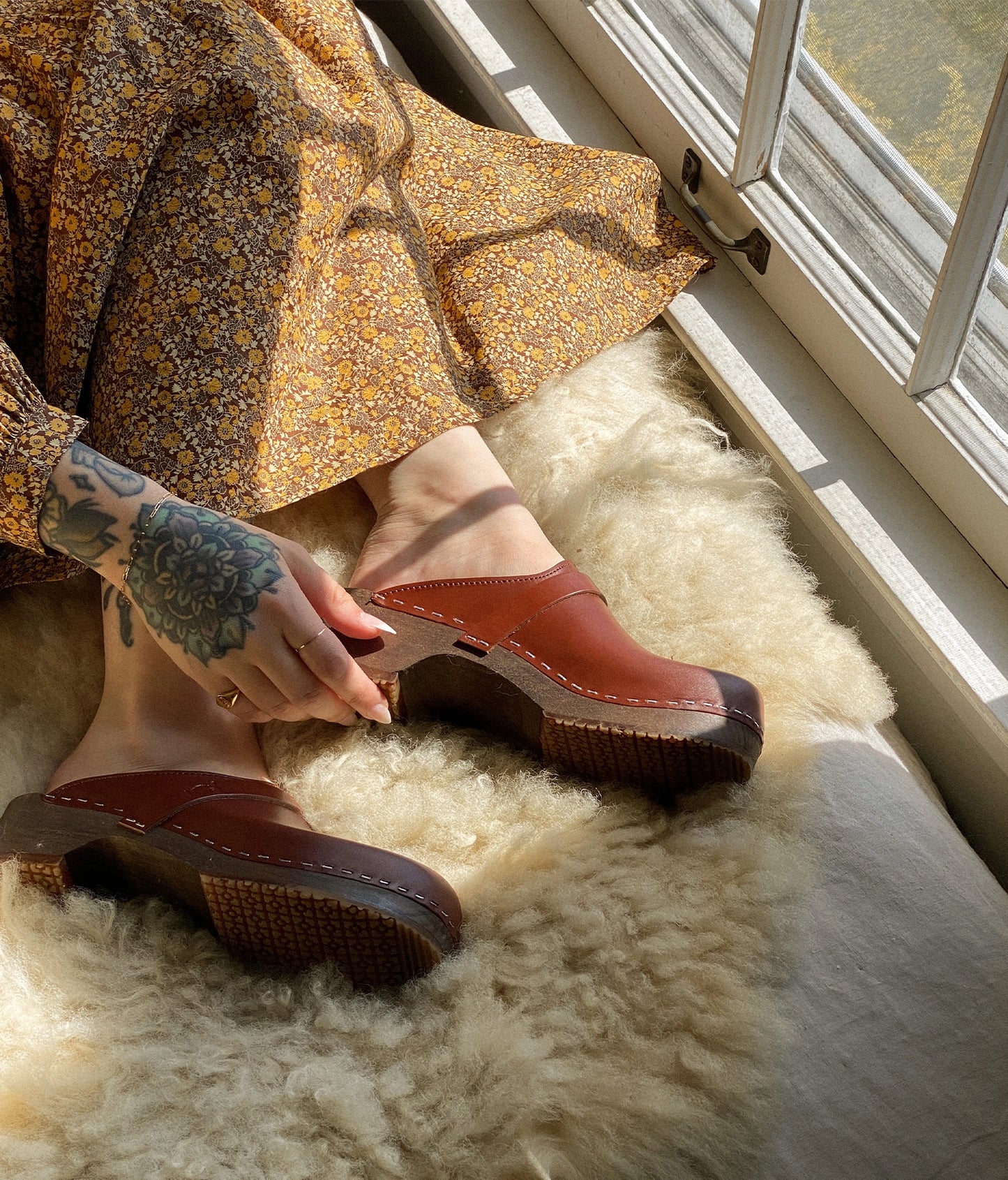 classic low heeled clog mule in cognac red vegetable tanned leather stapled on a dark wooden base with a leather strap