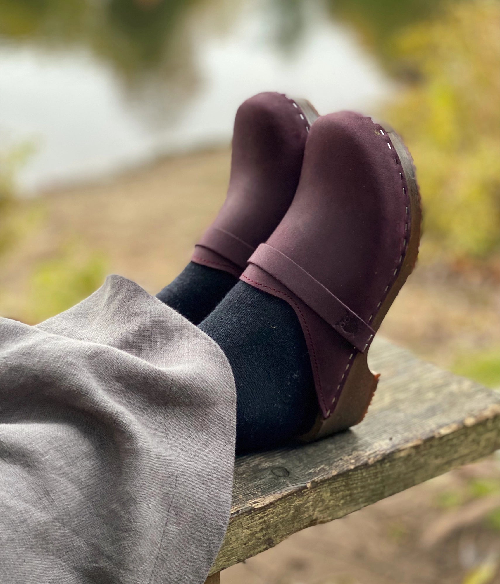 classic low heeled clog mule in plum purple nubuck leather stapled on a dark wooden base with a leather strap