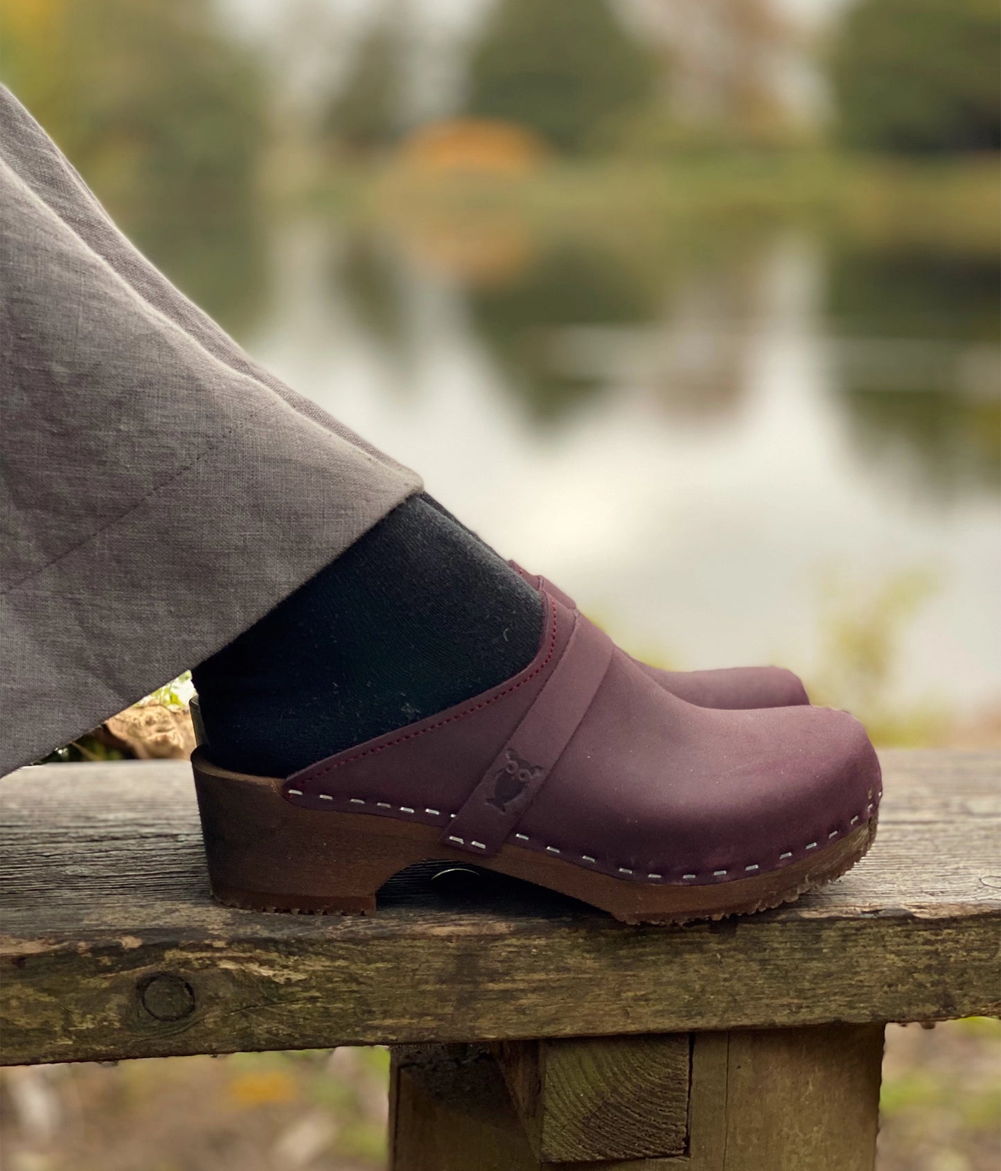 classic low heeled clog mule in plum purple nubuck leather stapled on a dark wooden base with a leather strap