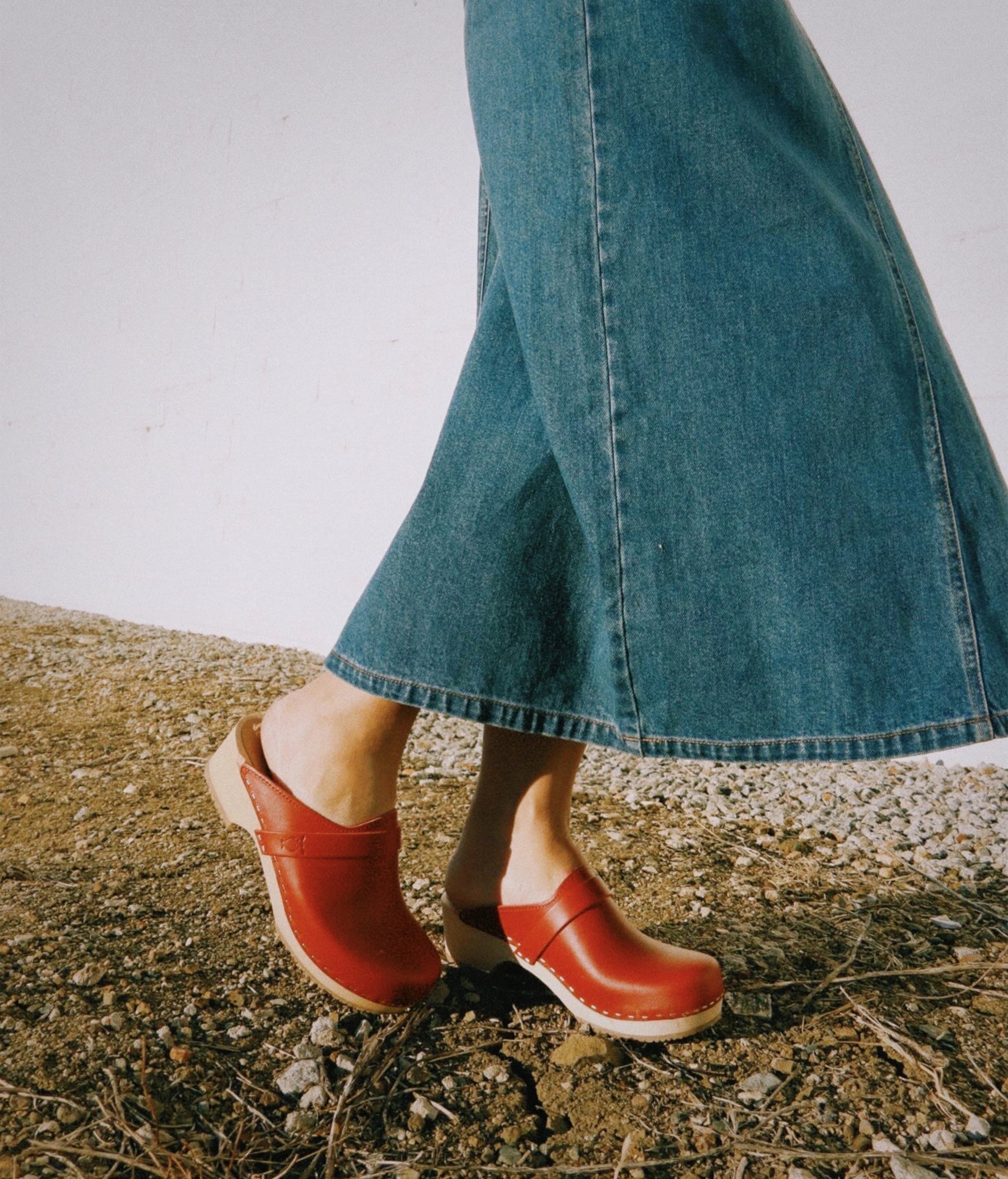 classic low heeled clog mule in red vegetable tanned leather stapled on a light wooden base with a leather strap