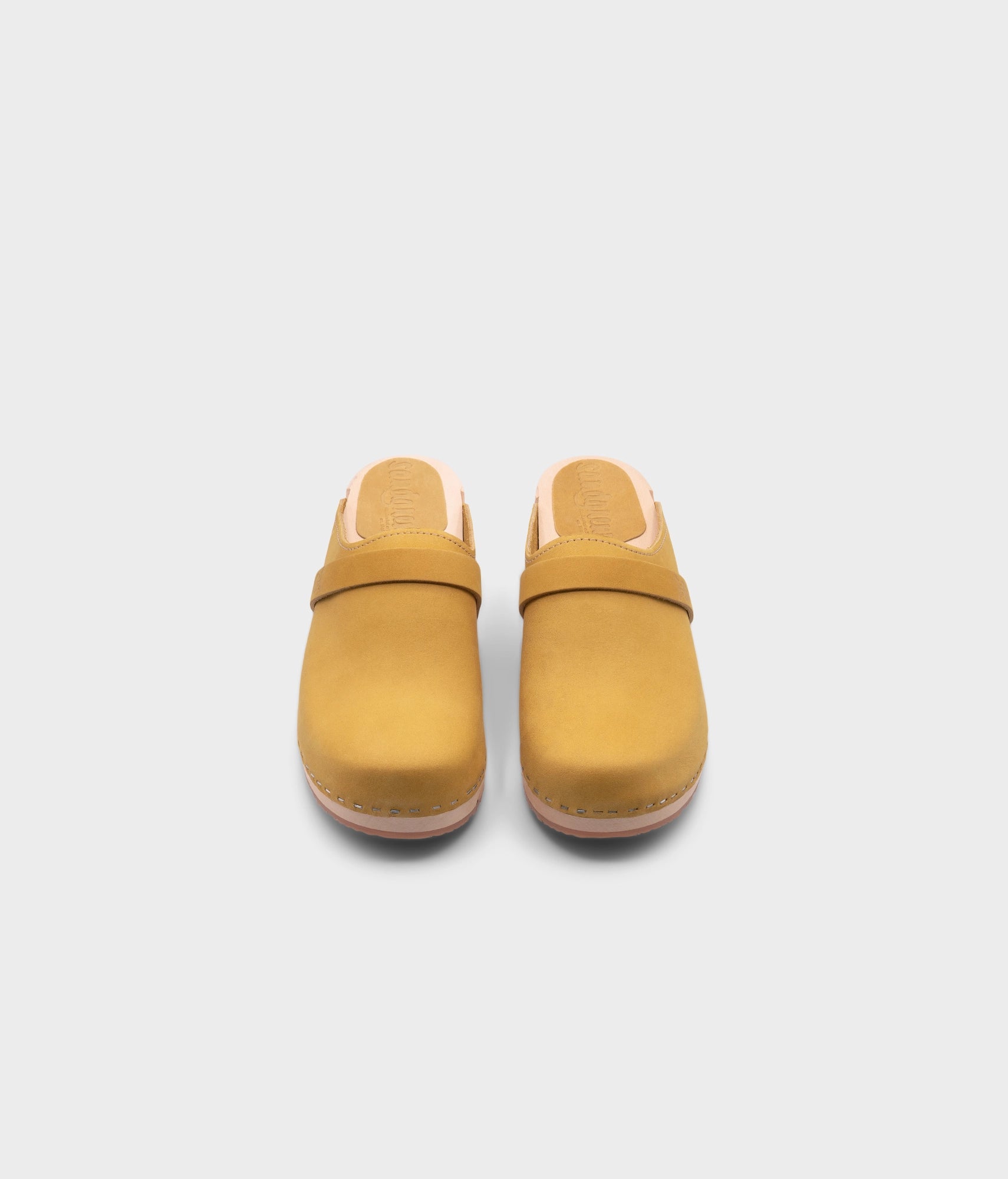 classic low heeled clog mule in yellow nubuck leather stapled on a light wooden base with a leather strap