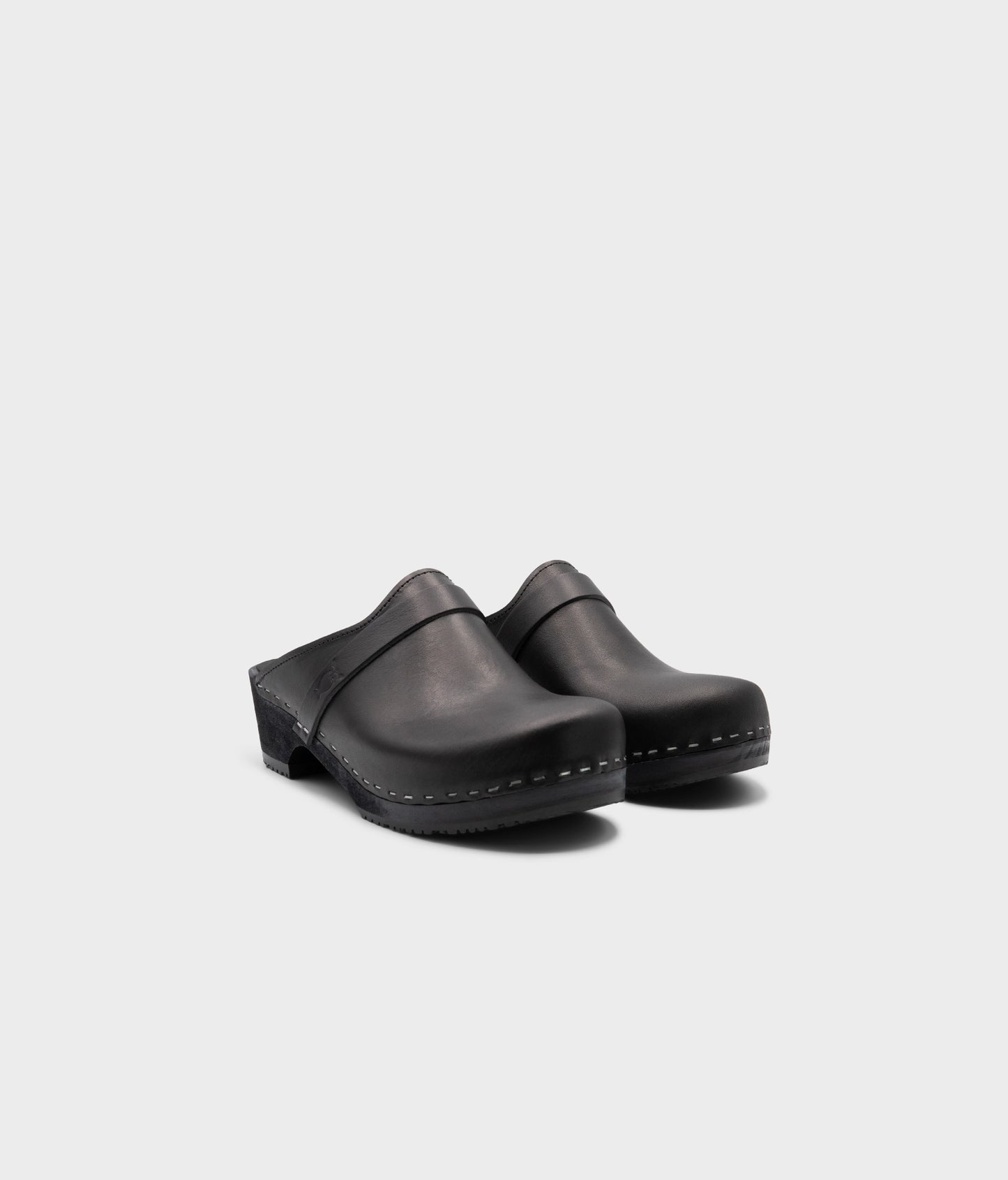 classic low heeled clog mule in black vegetable tanned leather stapled on a black wooden base with a leather strap