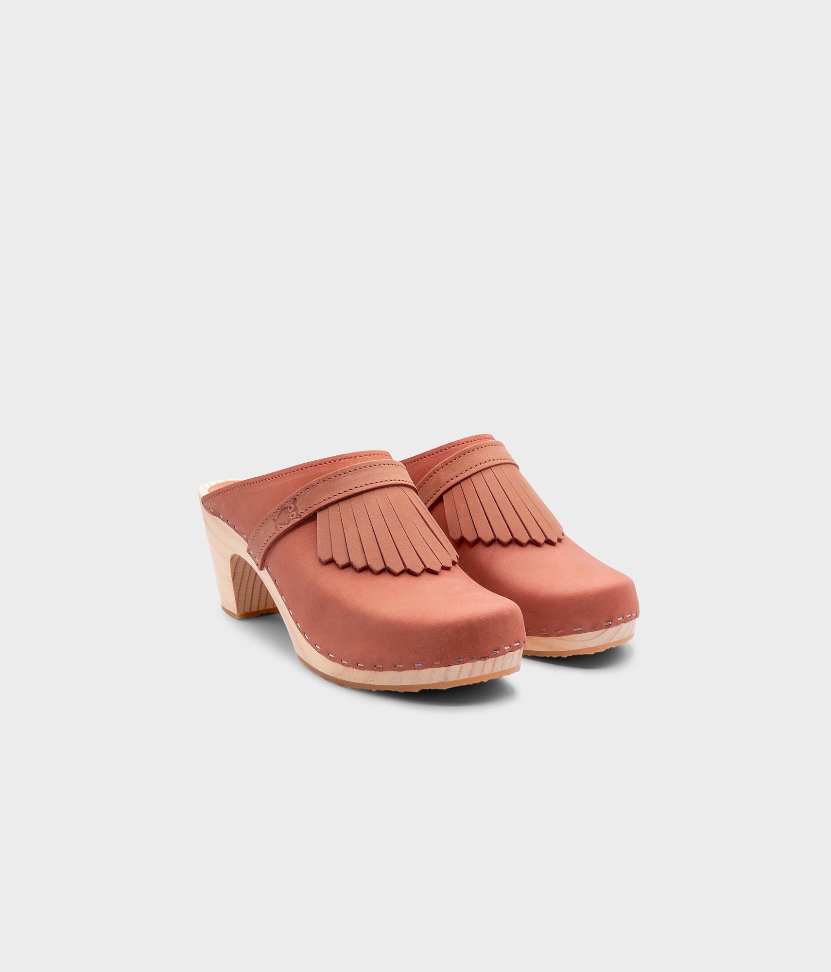 high rise clog mule in blush pink nubuck leather stapled on a light wooden base with a leather strap with fringes