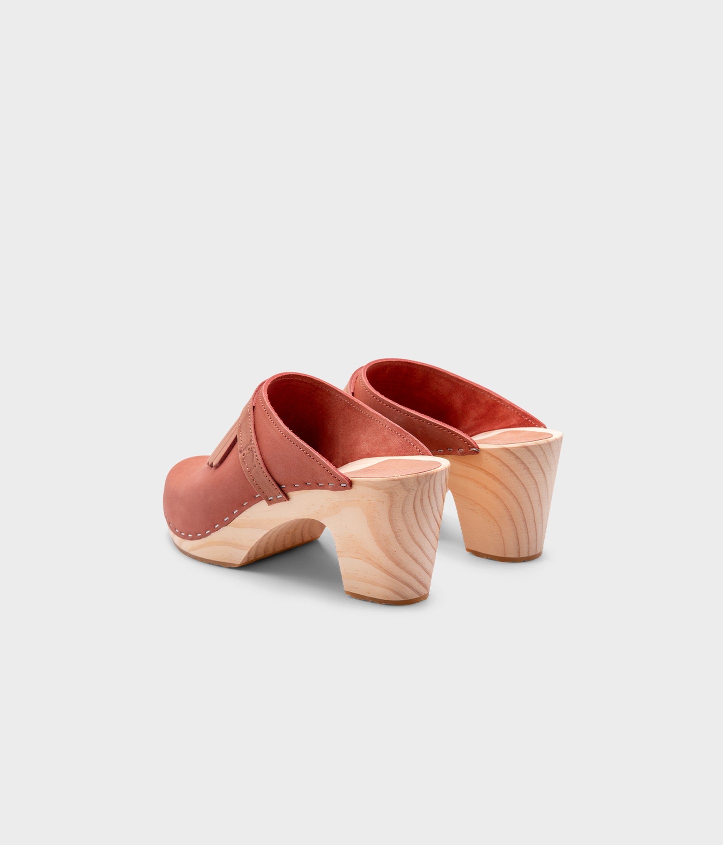 high rise clog mule in blush pink nubuck leather stapled on a light wooden base with a leather strap with fringes