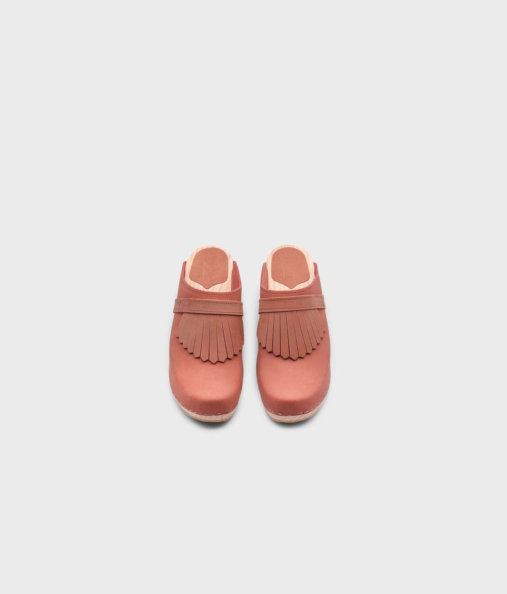 high rise clog mule in blush pink nubuck leather stapled on a light wooden base with a leather strap with fringes