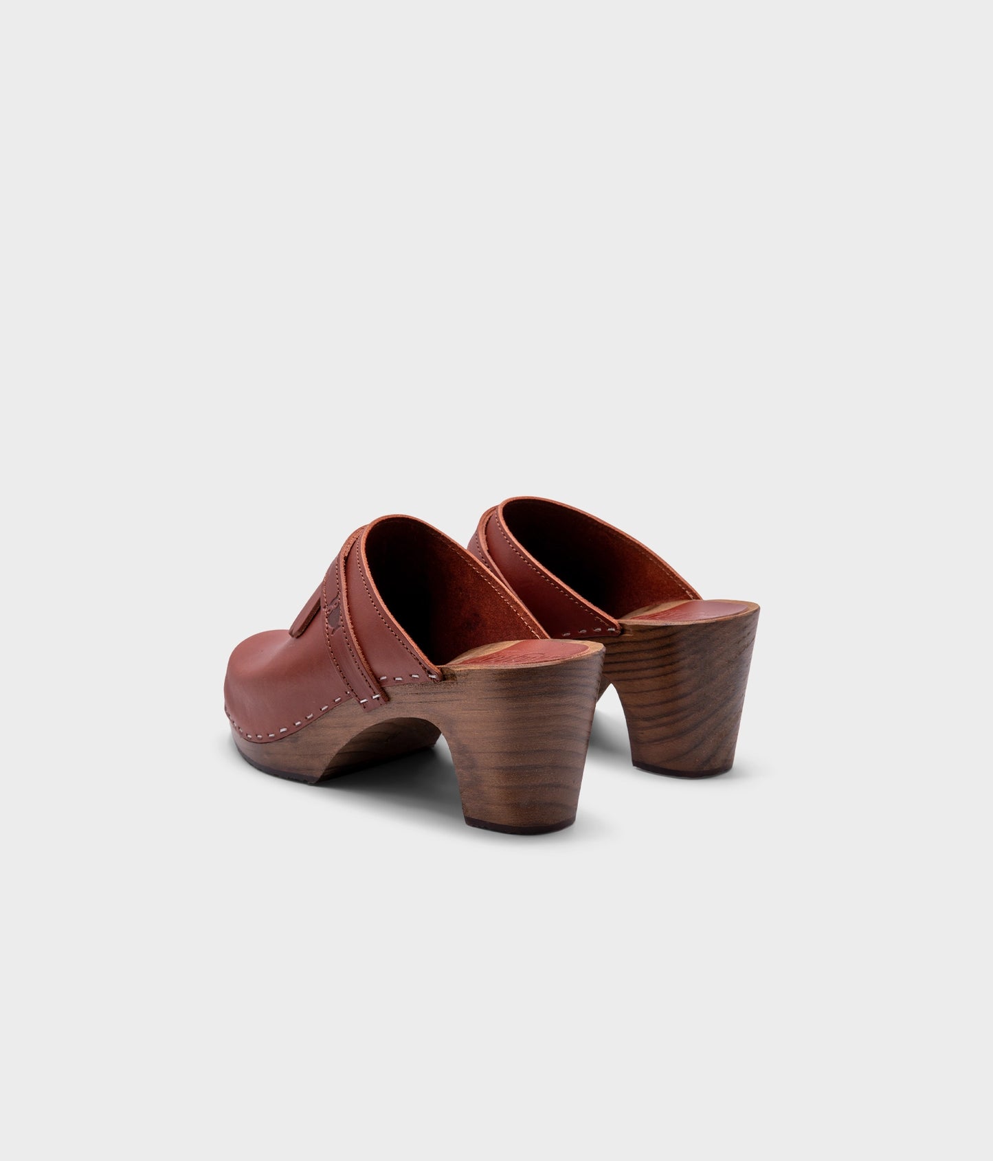 high rise clog mule in cognac red vegetable tanned leather stapled on a dark wooden base with a leather strap with fringes