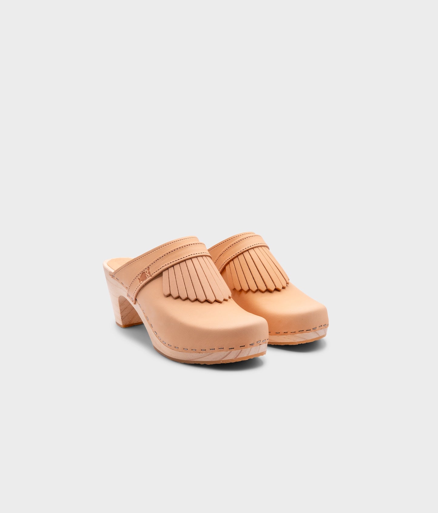 high rise clog mule in ecru beige vegetable tanned leather stapled on a light wooden base with a leather strap with fringes