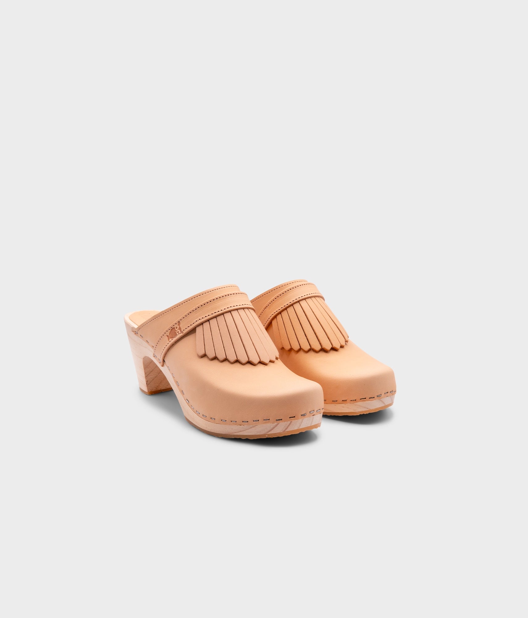 high rise clog mule in ecru beige vegetable tanned leather stapled on a light wooden base with a leather strap with fringes