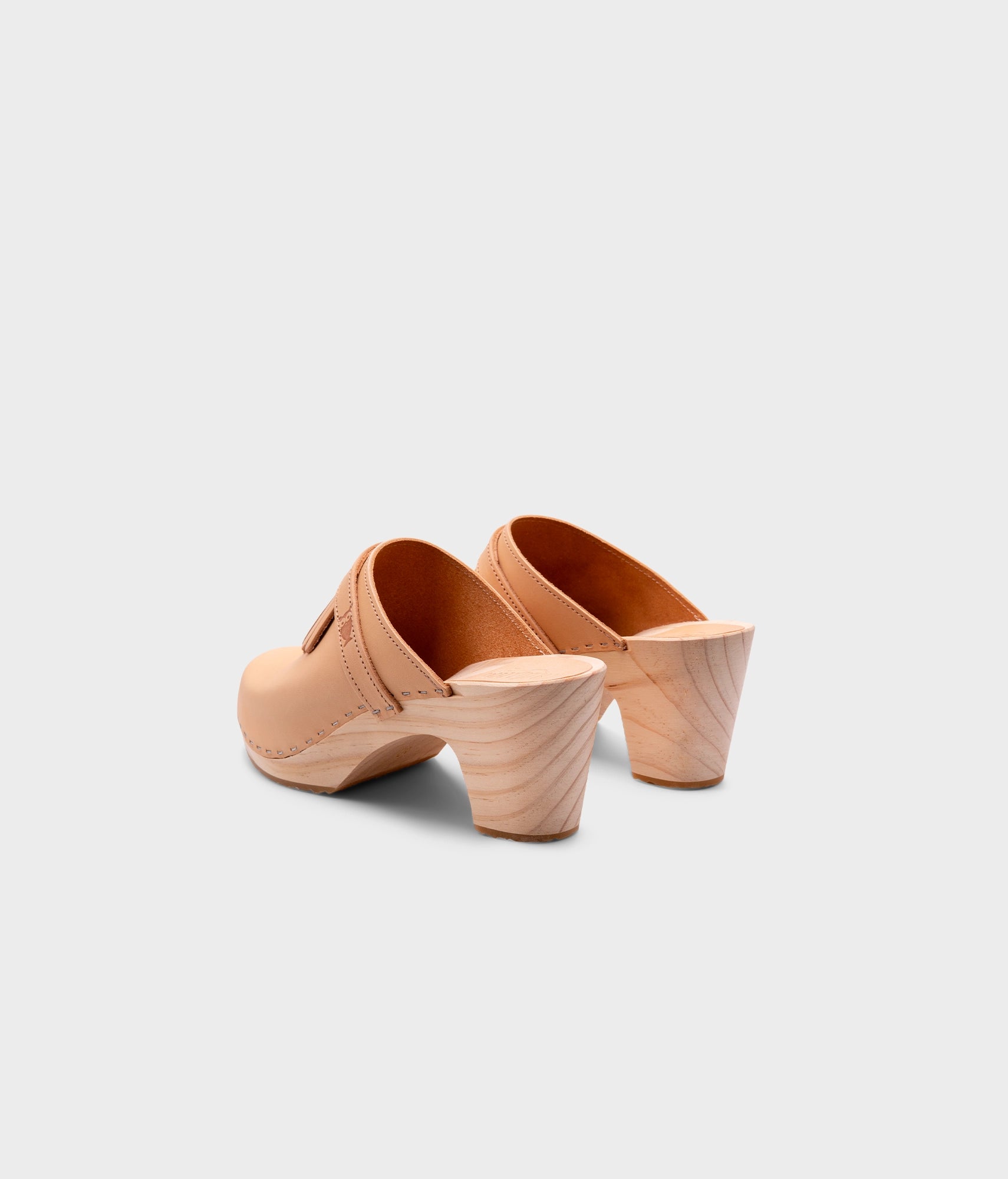 high rise clog mule in ecru beige vegetable tanned leather stapled on a light wooden base with a leather strap with fringes