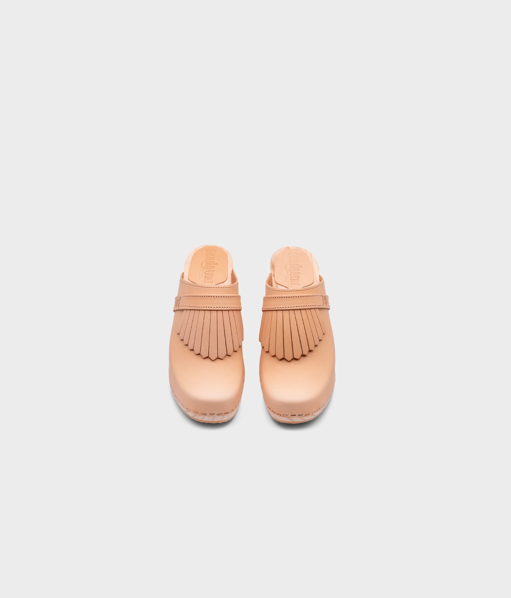 high rise clog mule in ecru beige vegetable tanned leather stapled on a light wooden base with a leather strap with fringes