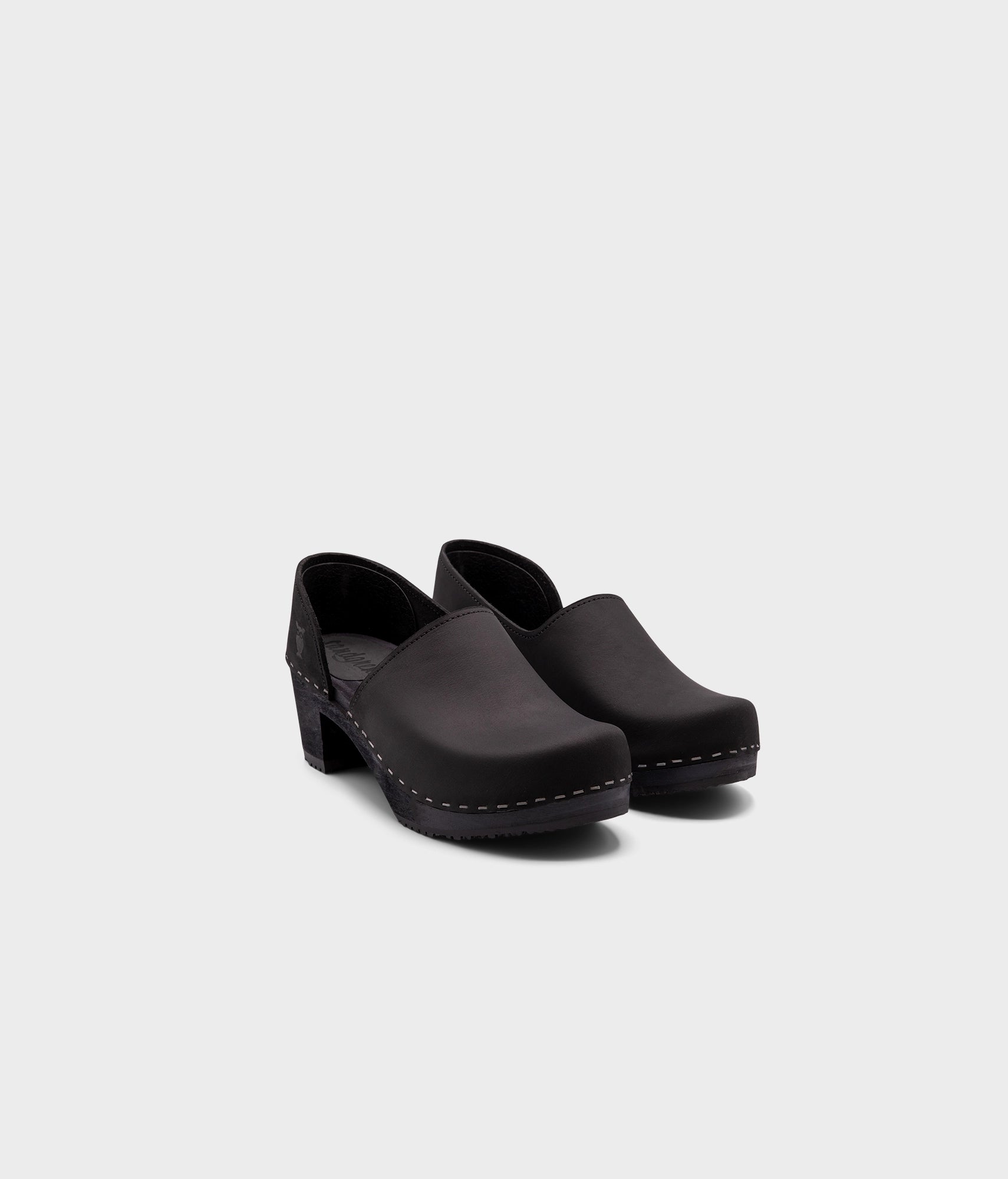 high heeled closed-back clogs in black nubuck leather stapled on a black wooden base