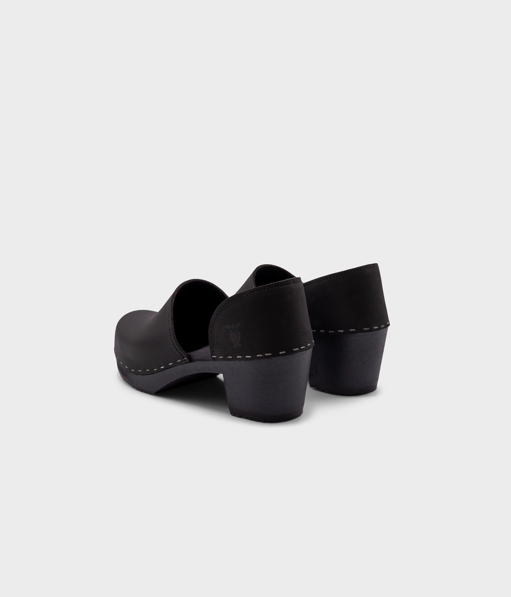 high heeled closed-back clogs in black nubuck leather stapled on a black wooden base