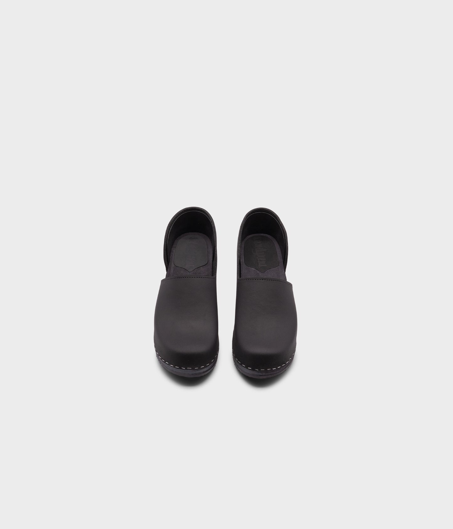 high heeled closed-back clogs in black nubuck leather stapled on a black wooden base