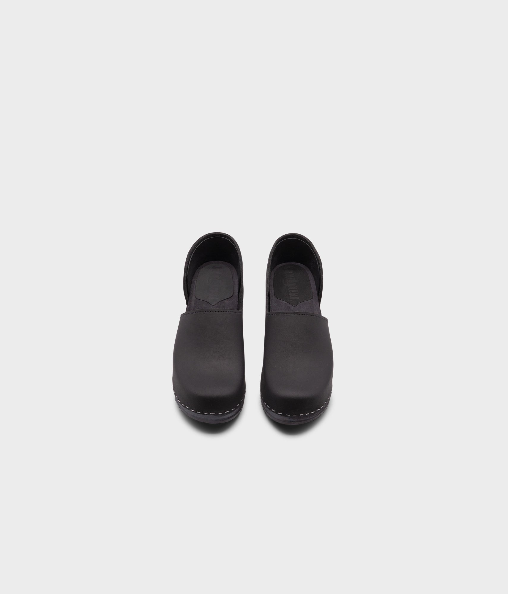 high heeled closed-back clogs in black nubuck leather stapled on a black wooden base