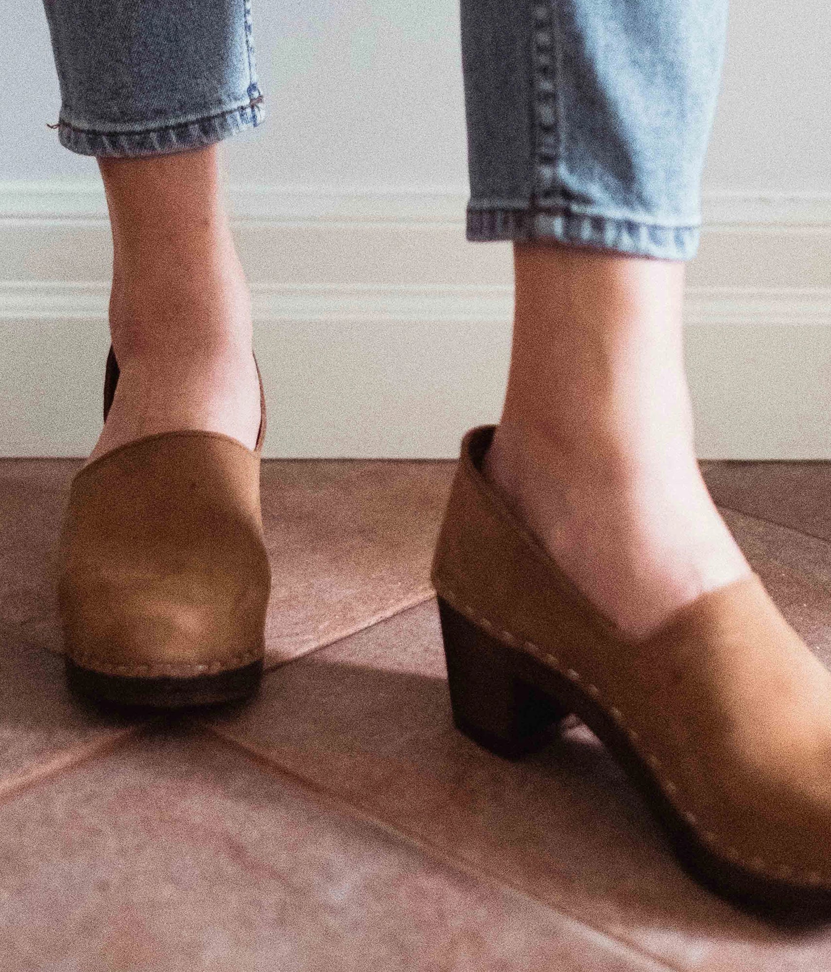 high heeled closed-back clogs in light brown nubuck leather stapled on a dark wooden base