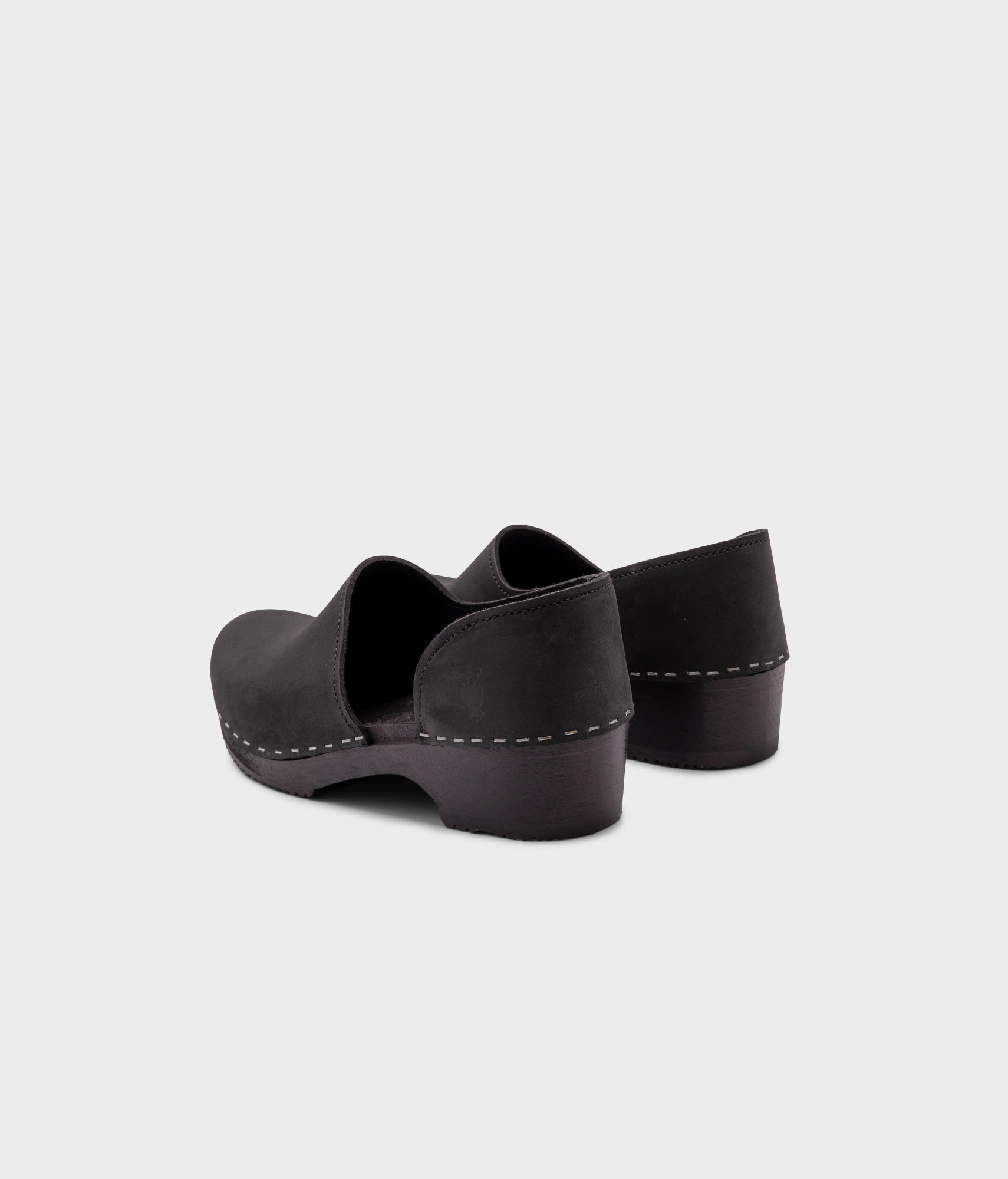 low heeled closed-back clogs in black nubuck leather stapled on a black wooden base