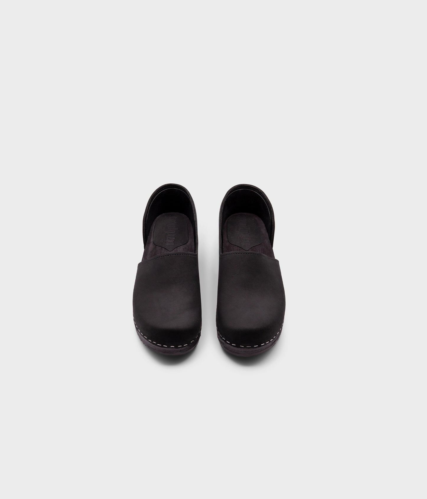 low heeled closed-back clogs in black nubuck leather stapled on a black wooden base