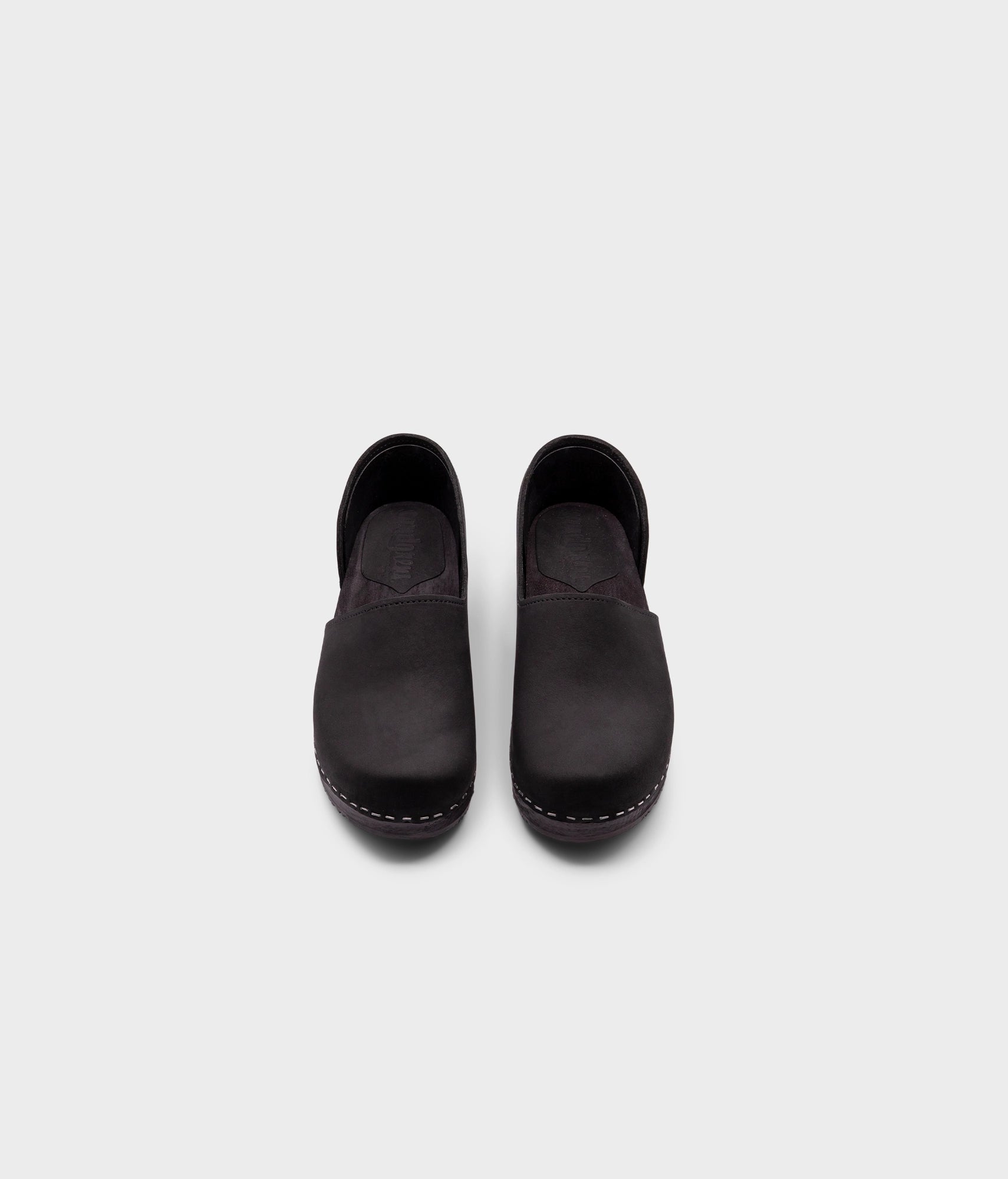 low heeled closed-back clogs in black nubuck leather stapled on a black wooden base
