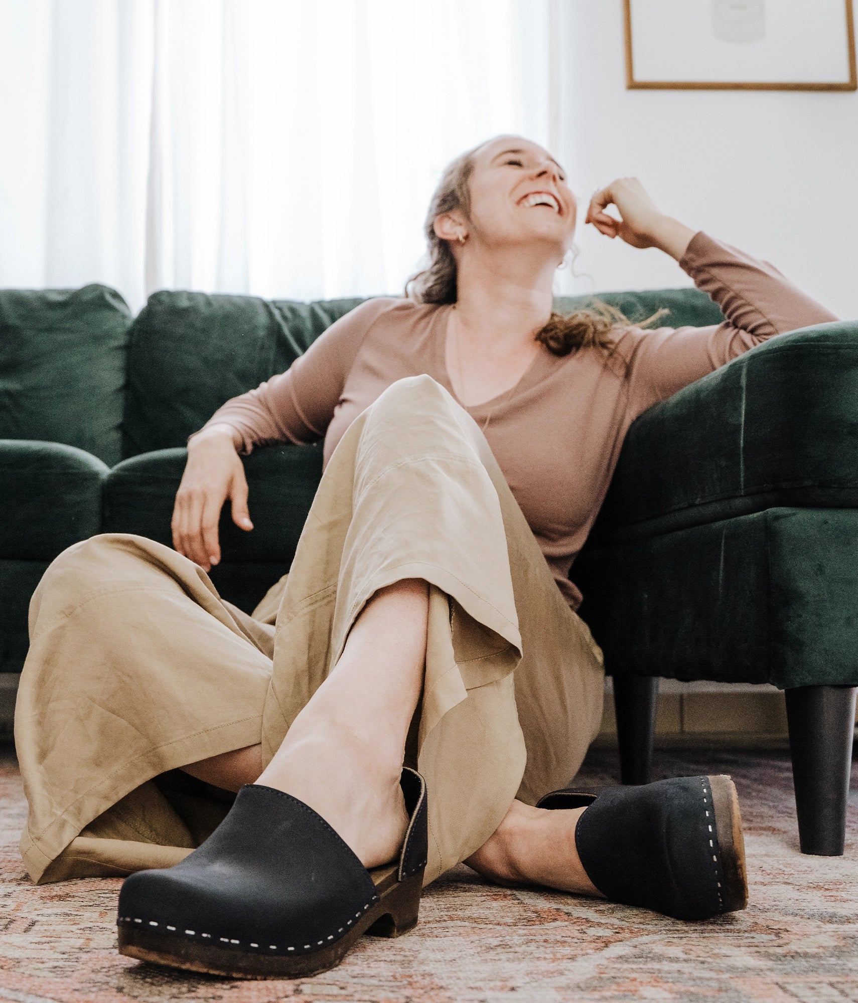 low heeled closed-back clogs in black nubuck leather stapled on a dark wooden base