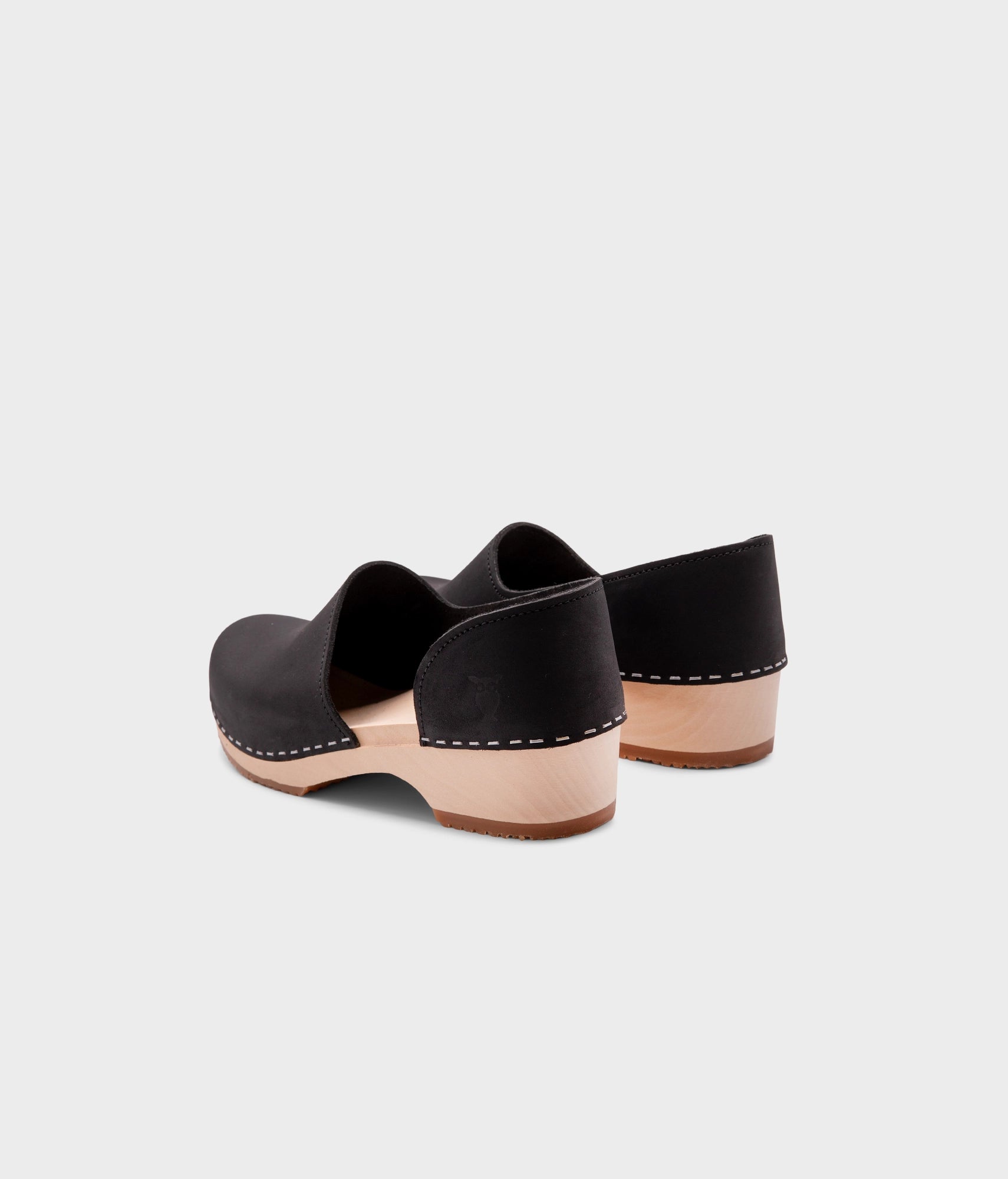 low heeled closed-back clogs in black nubuck leather stapled on a light wooden base