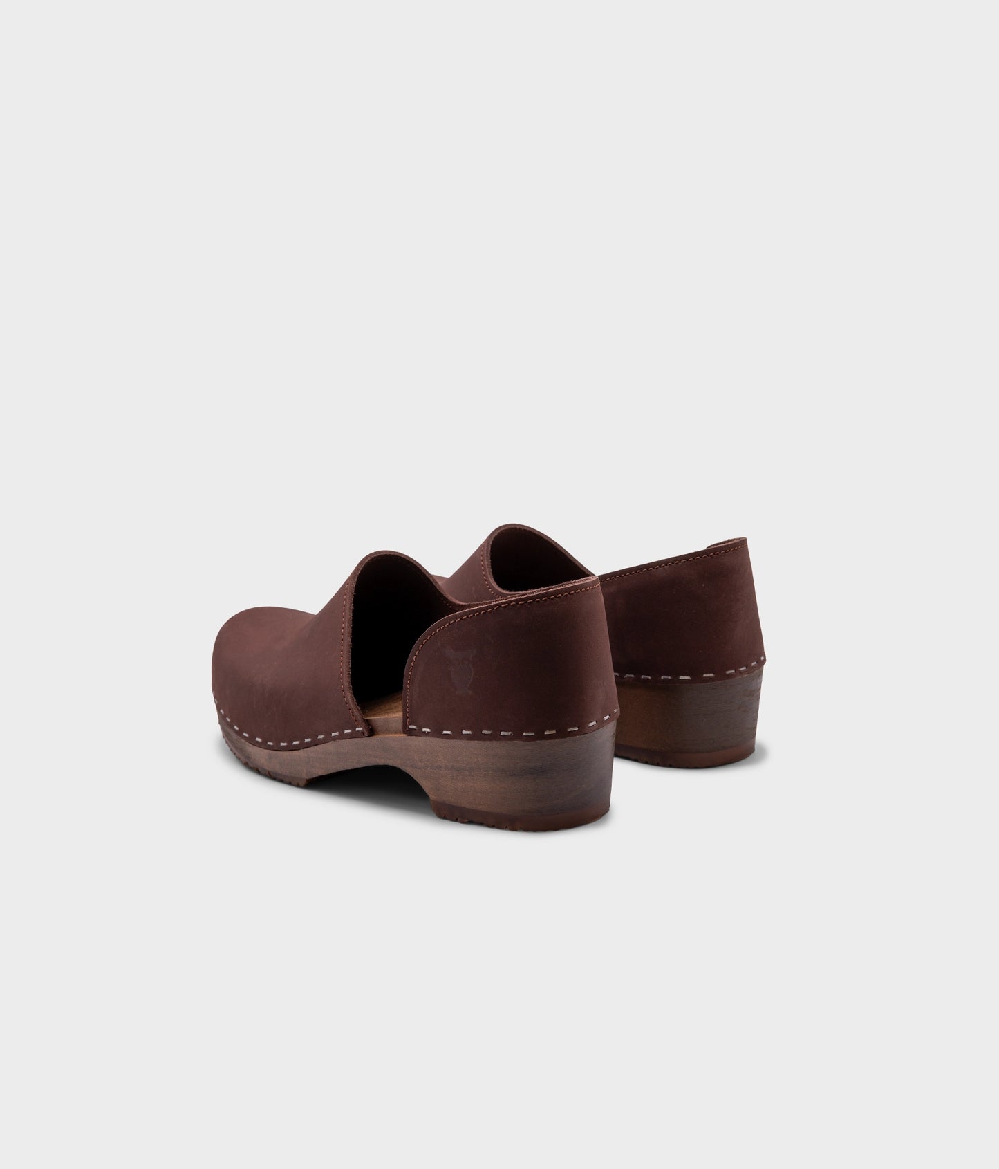 low heeled closed-back clogs in dark brown nubuck leather stapled on a dark wooden base