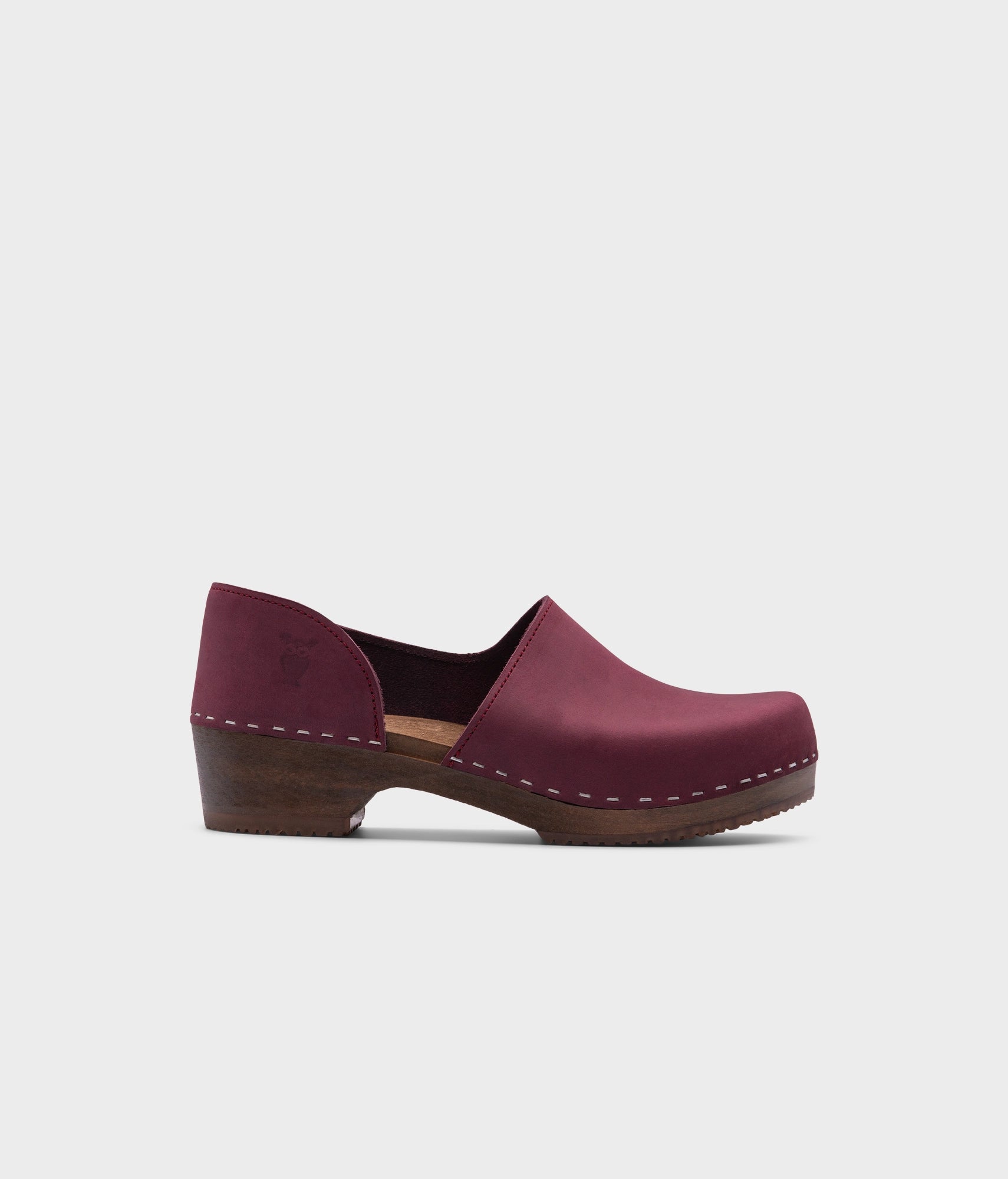 low heeled closed-back clogs in dark purple nubuck leather stapled on a dark wooden base
