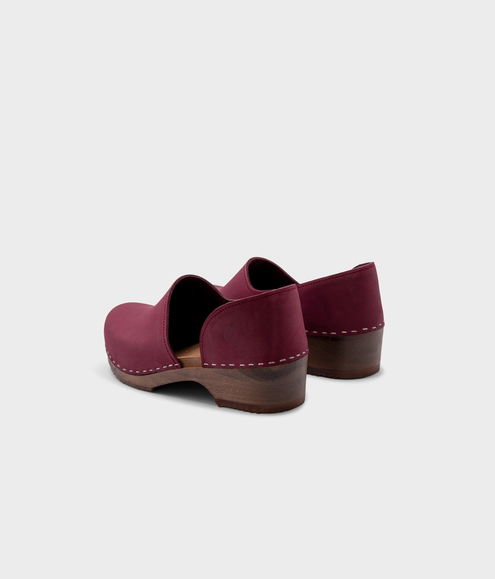 low heeled closed-back clogs in dark purple nubuck leather stapled on a dark wooden base