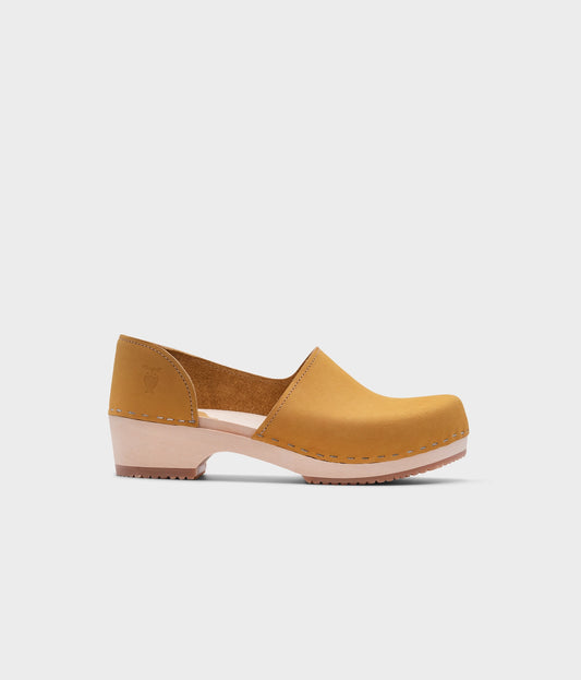 low heeled closed-back clogs in yellow nubuck leather stapled on a light wooden base