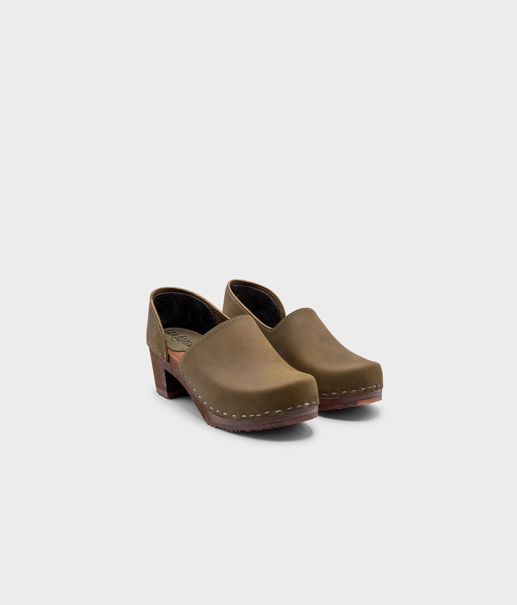 high heeled closed-back clogs in olive green nubuck leather stapled on a dark wooden base