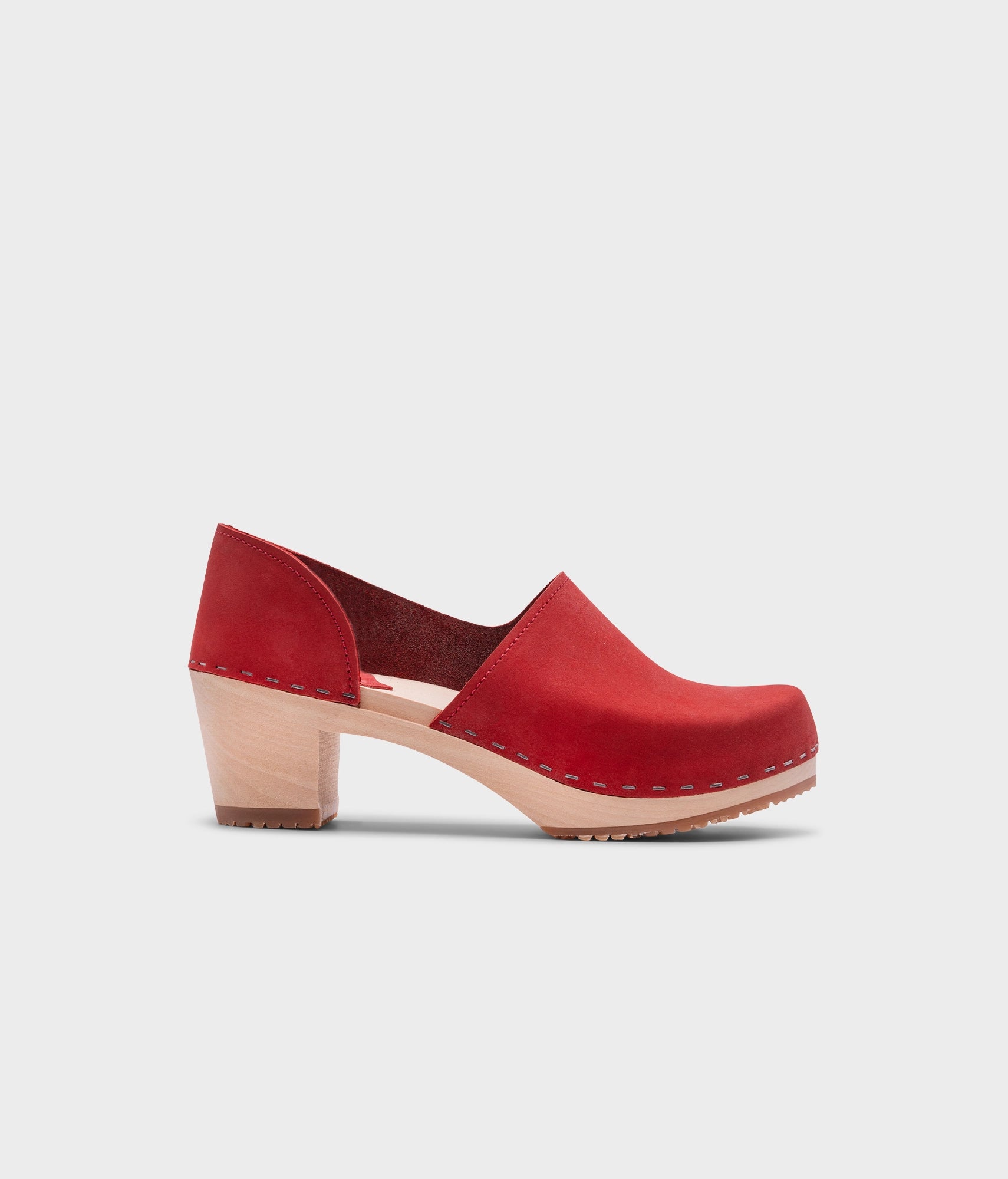 high heeled closed-back clogs in red nubuck leather stapled on a light wooden base
