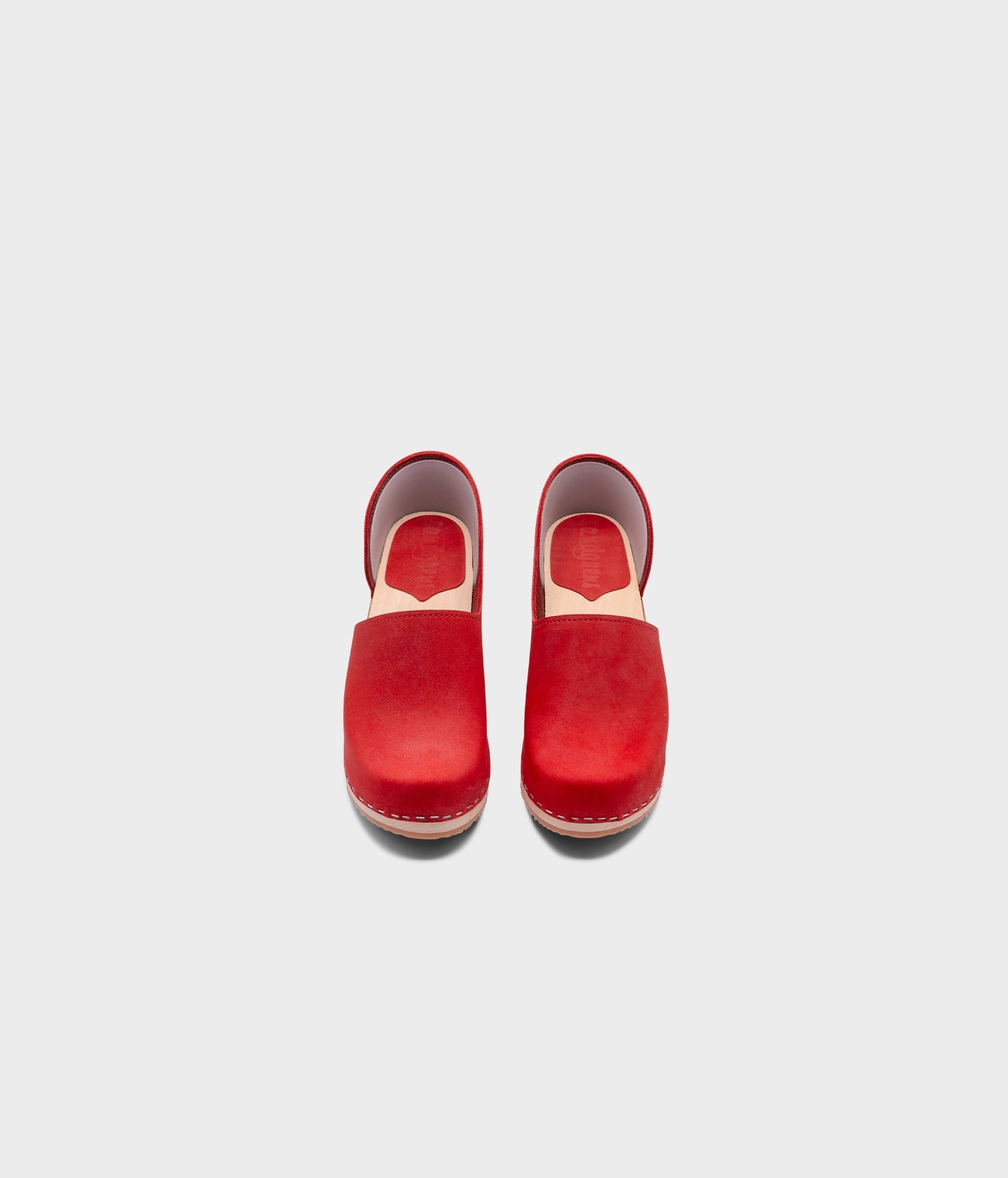high heeled closed-back clogs in red nubuck leather stapled on a light wooden base