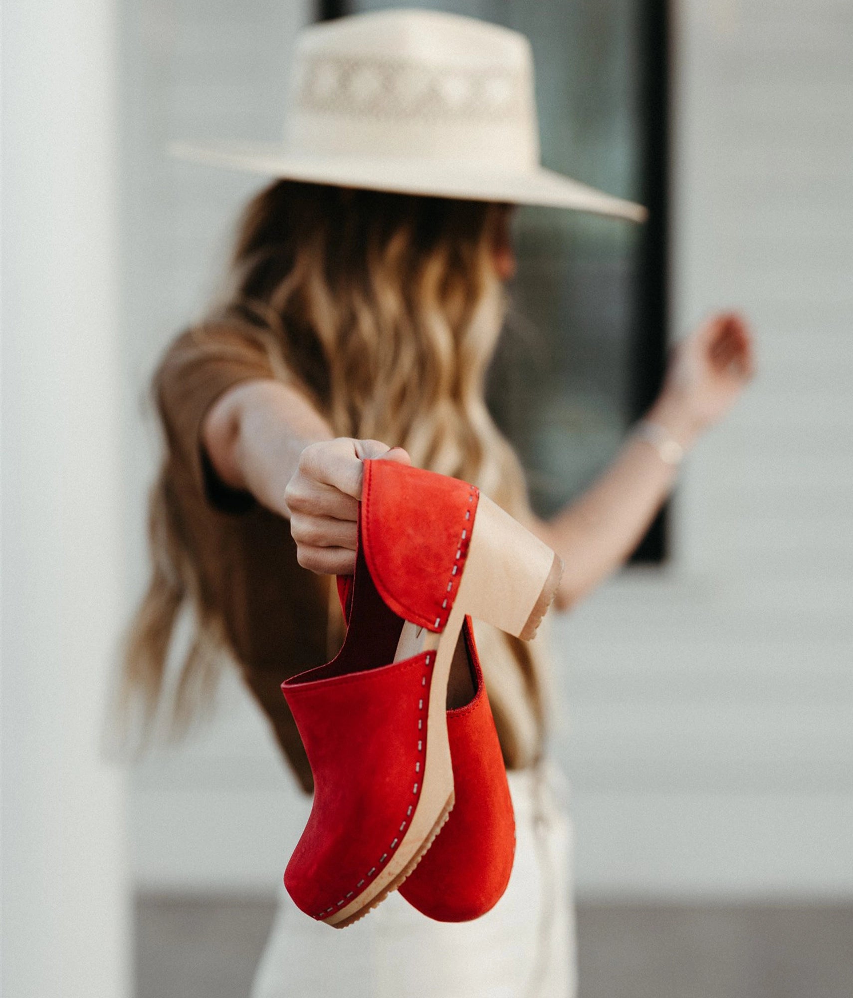 high heeled closed-back clogs in red nubuck leather stapled on a light wooden base