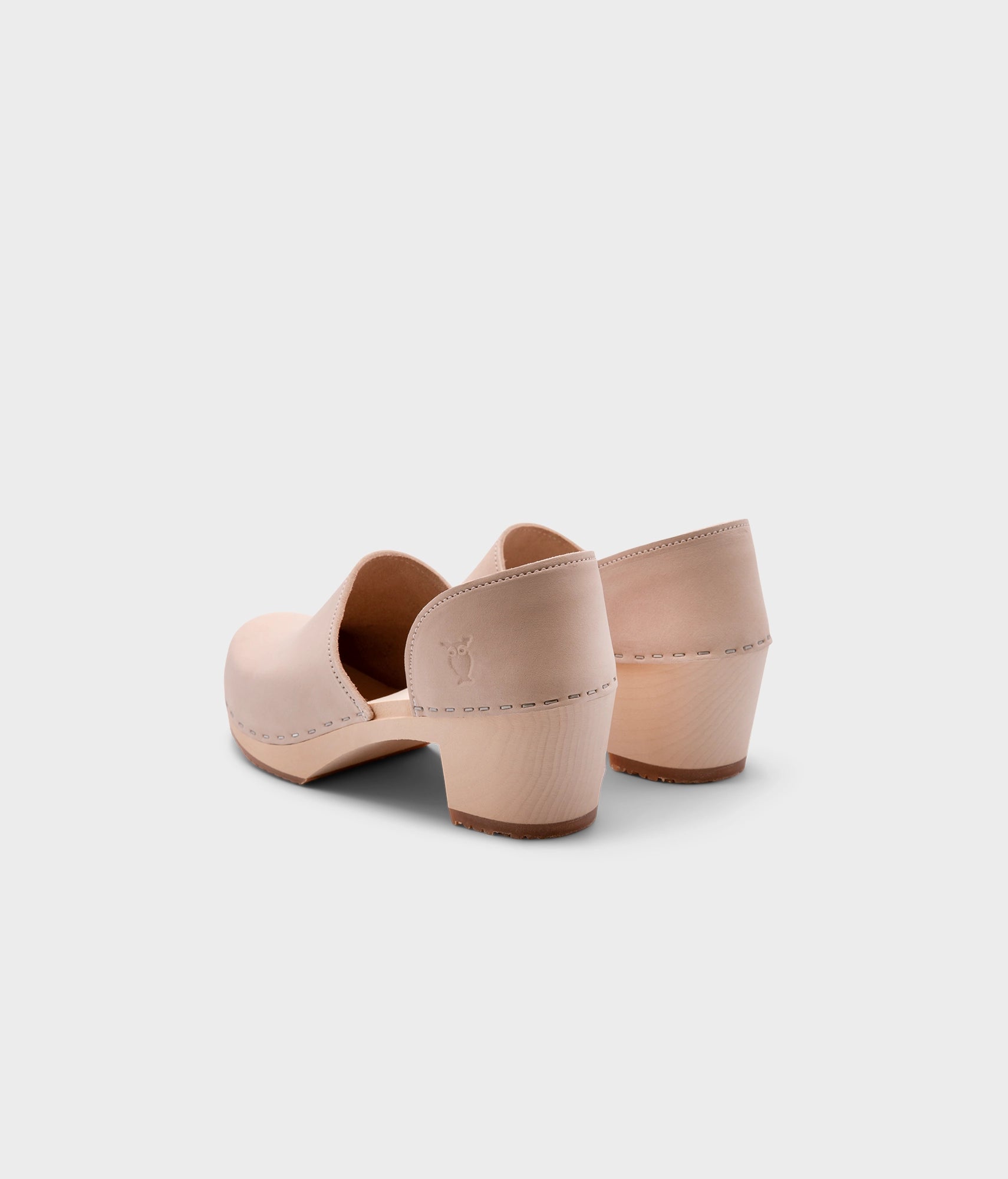 high heeled closed-back clogs in sand white nubuck leather stapled on a light wooden base