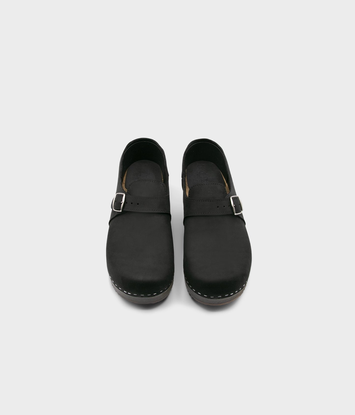 men's closed-back clogs in black nubuck leather stapled on a dark wooden base with a silver buckle