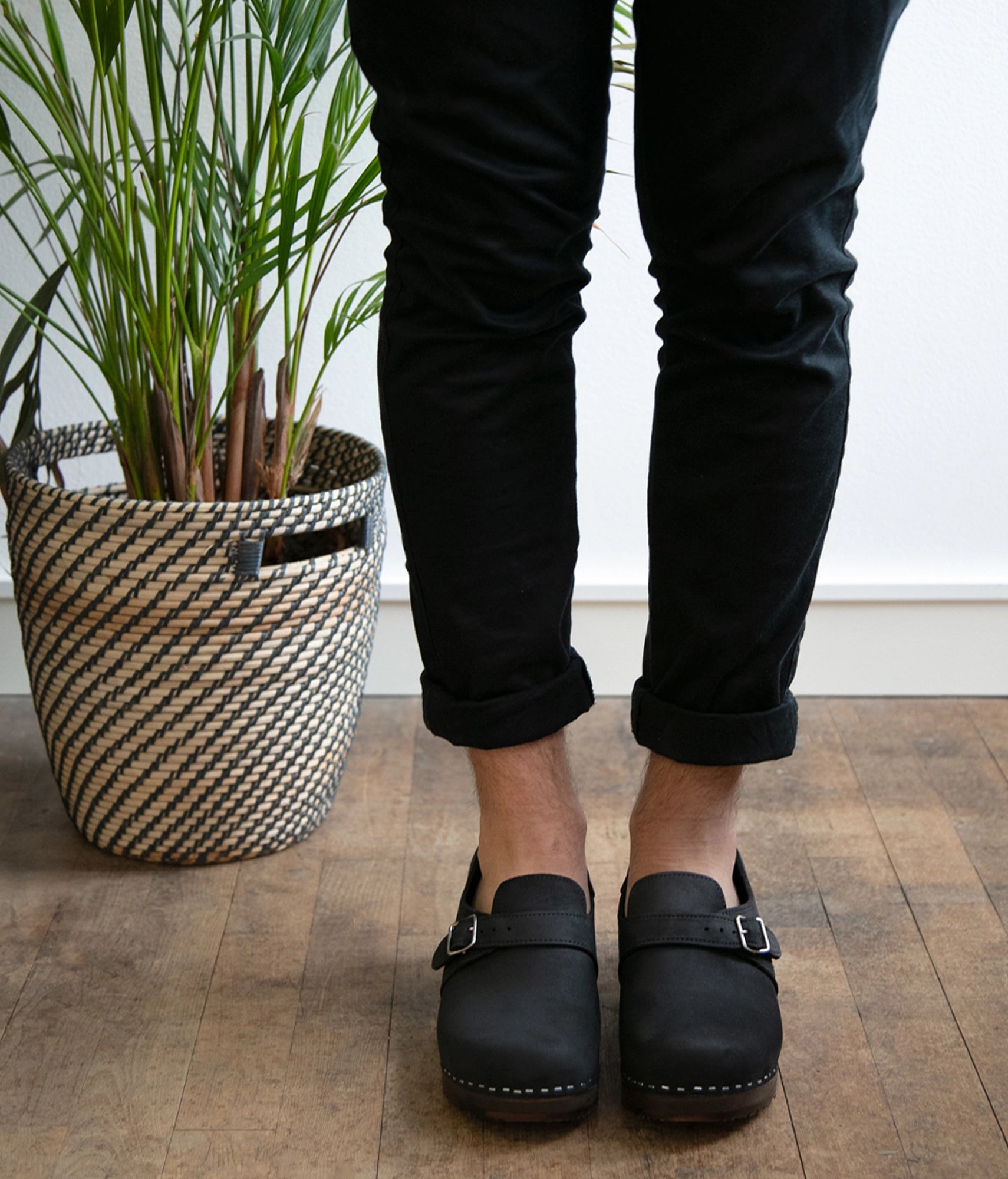 men's closed-back clogs in black nubuck leather stapled on a dark wooden base with a silver buckle