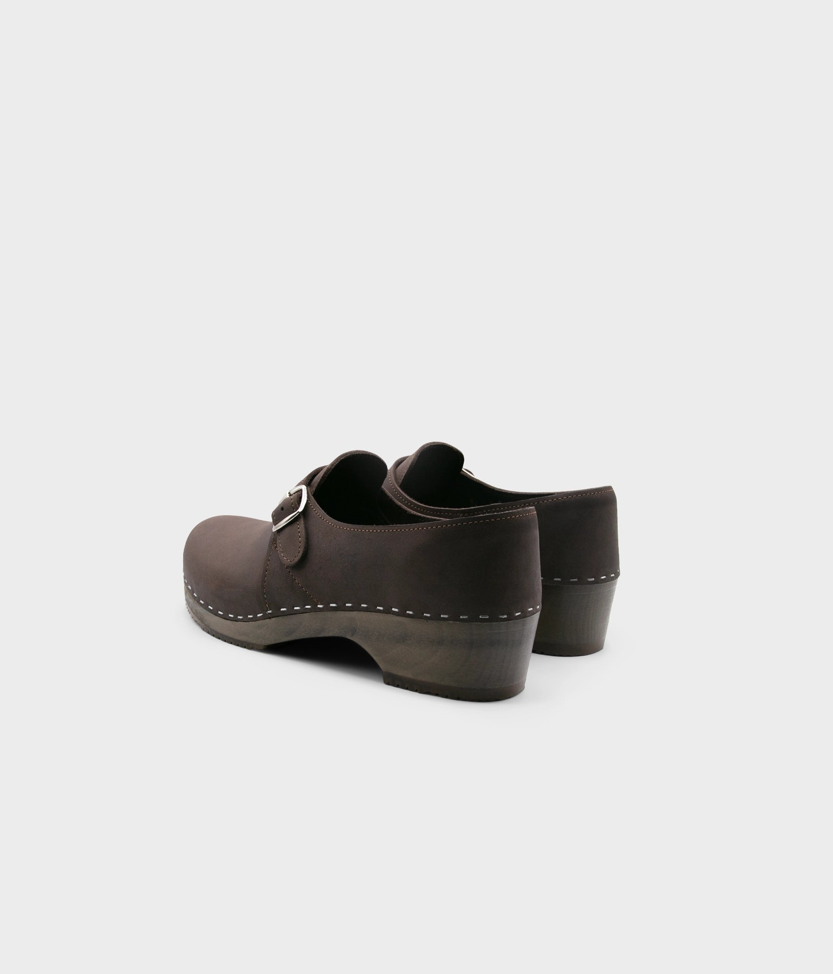 men's closed-back clogs in fudge brown nubuck leather stapled on a dark wooden base with a silver buckle