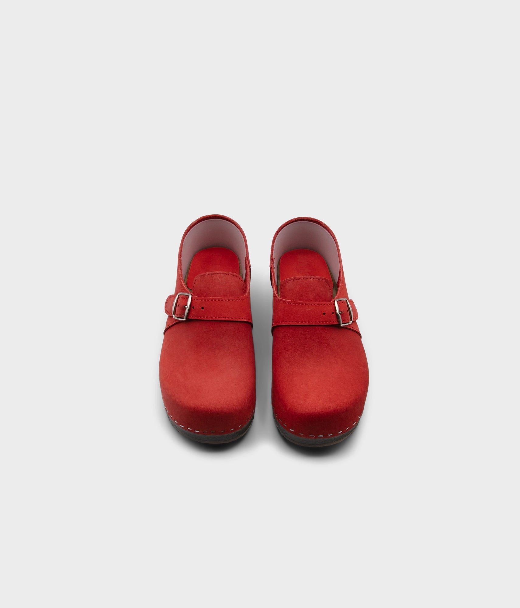 men's closed-back clogs in red nubuck leather stapled on a dark wooden base with a silver buckle