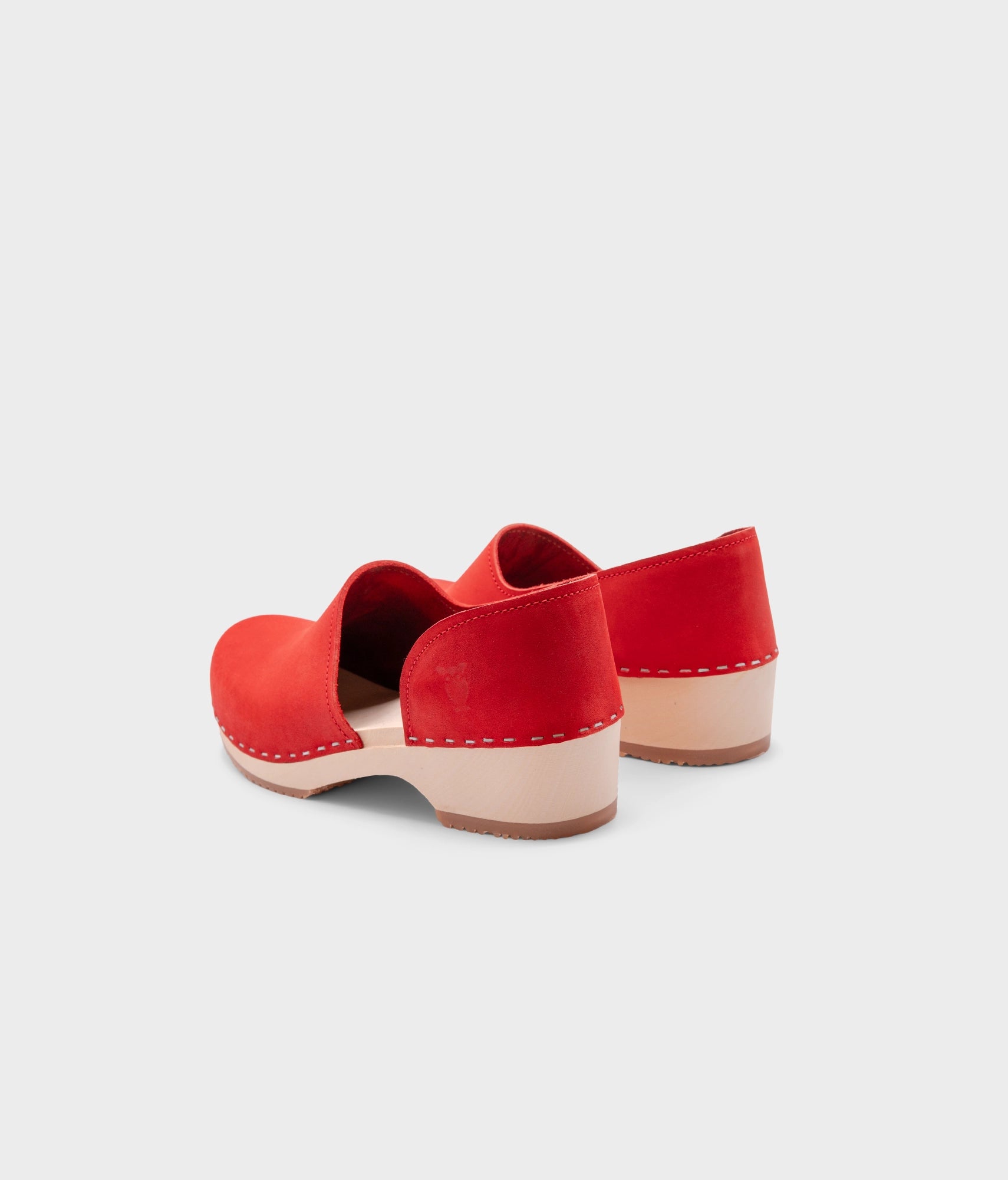 low heeled closed-back clogs in red nubuck leather stapled on a light wooden base