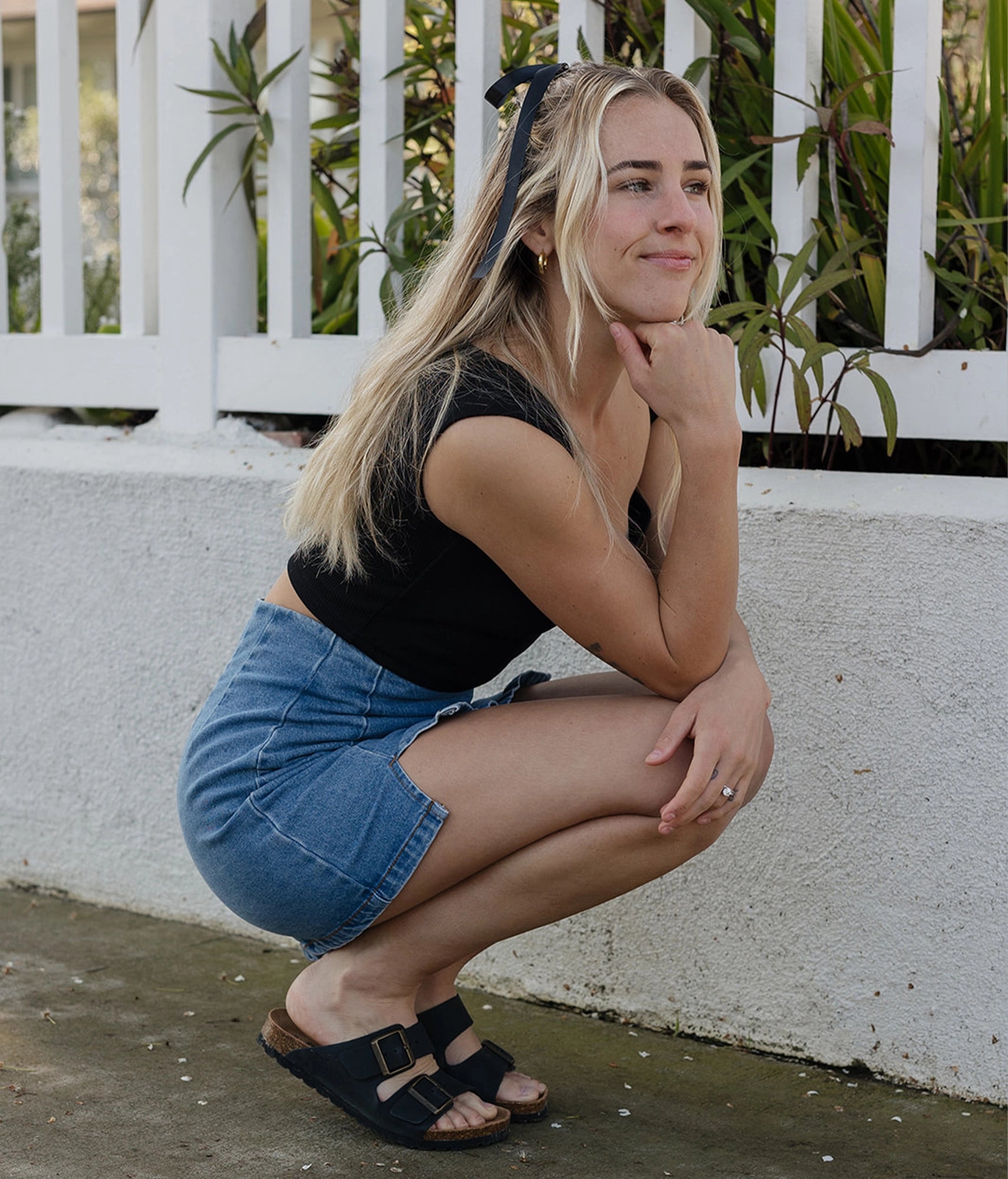 woman wearing a short jean skirt with a pair of classic cork sandals in black nubuck leather with a black EVA bottom and suede footbed