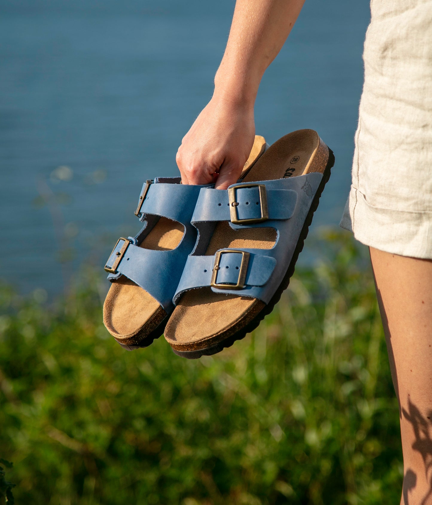 classic cork sandal with two straps in full-grain blue nubuck leather with a blue tint, suede footbed and brass gold buckles